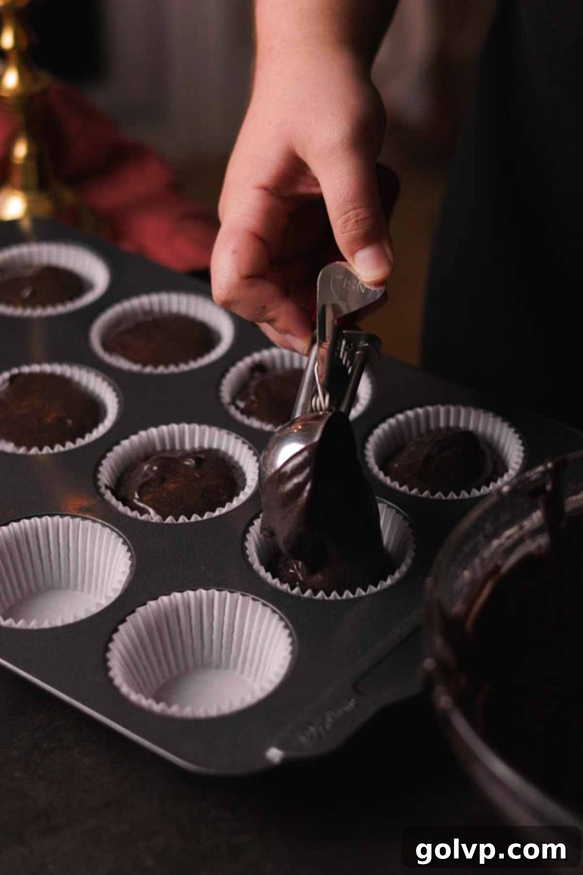 scooping cupcake batter into lined muffin tray