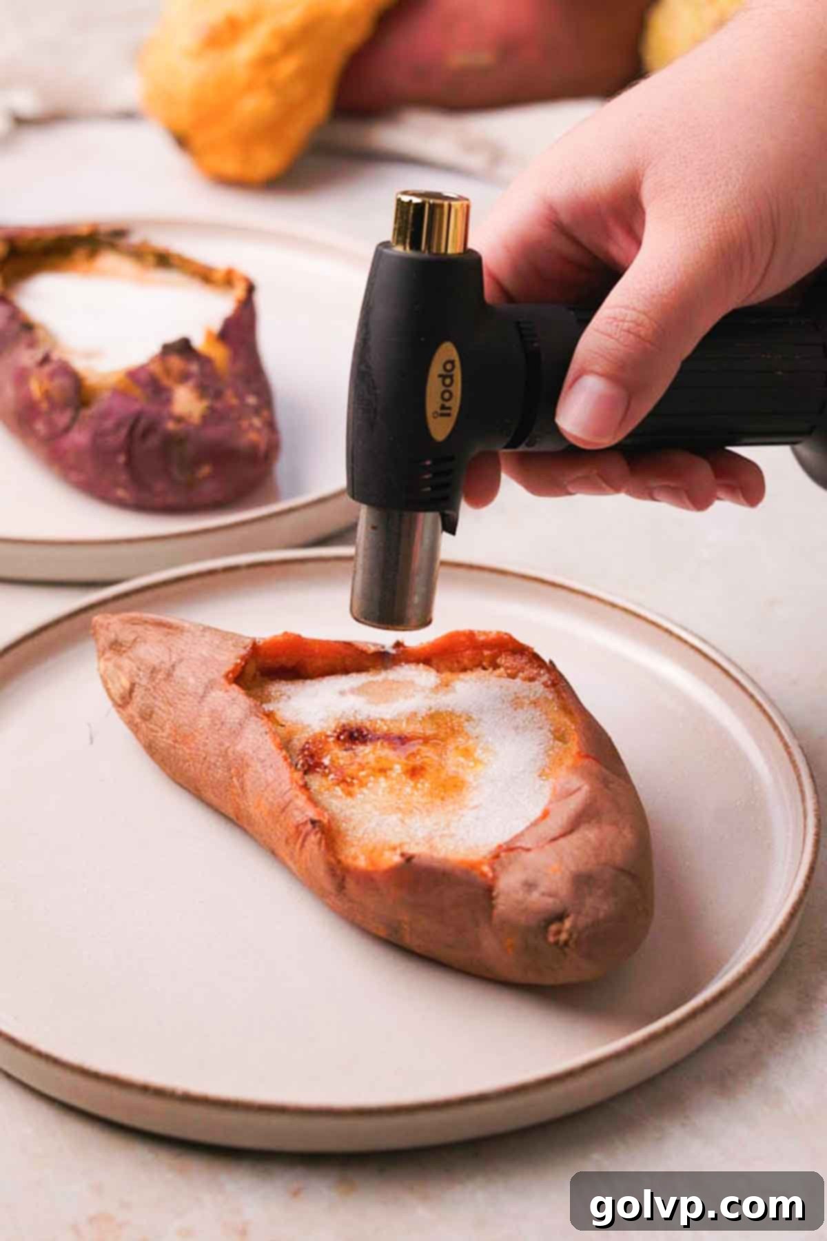 A kitchen torch caramelizing the sugar on top of a sweet potato crème brûlée.