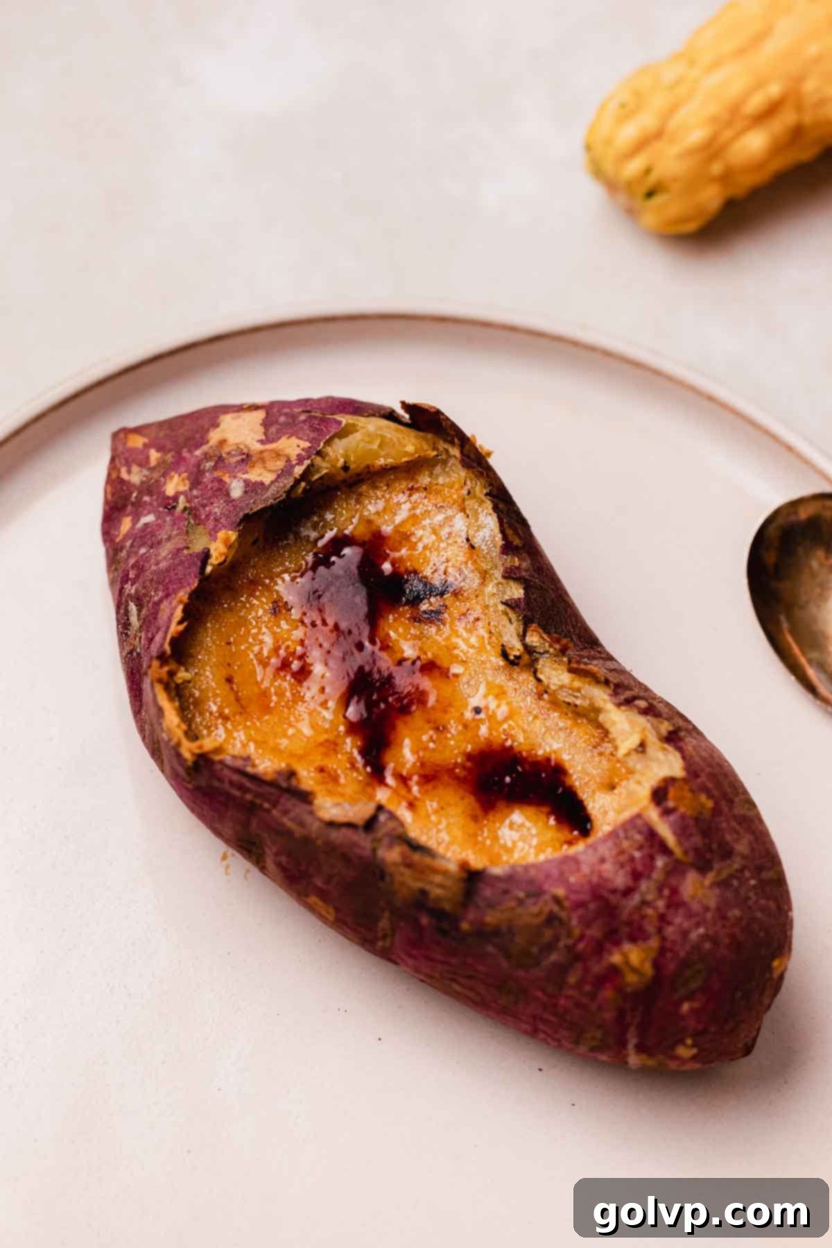 Close-up of a sweet potato crème brûlée, showing the crisp, caramelized sugar topping cracked open to reveal the smooth, creamy custard inside.