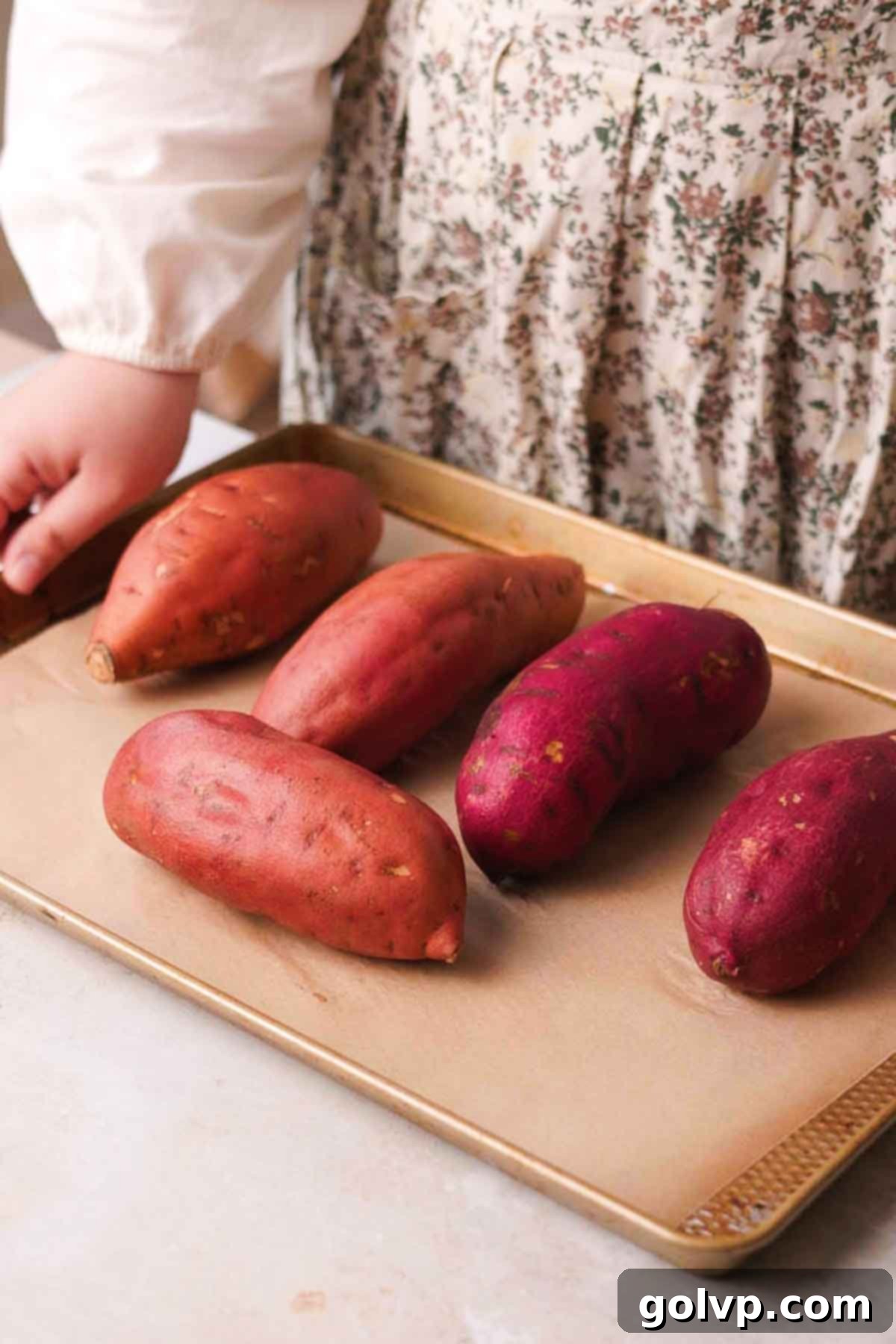 Sweet potatoes arranged on a parchment-lined baking sheet, ready for roasting.