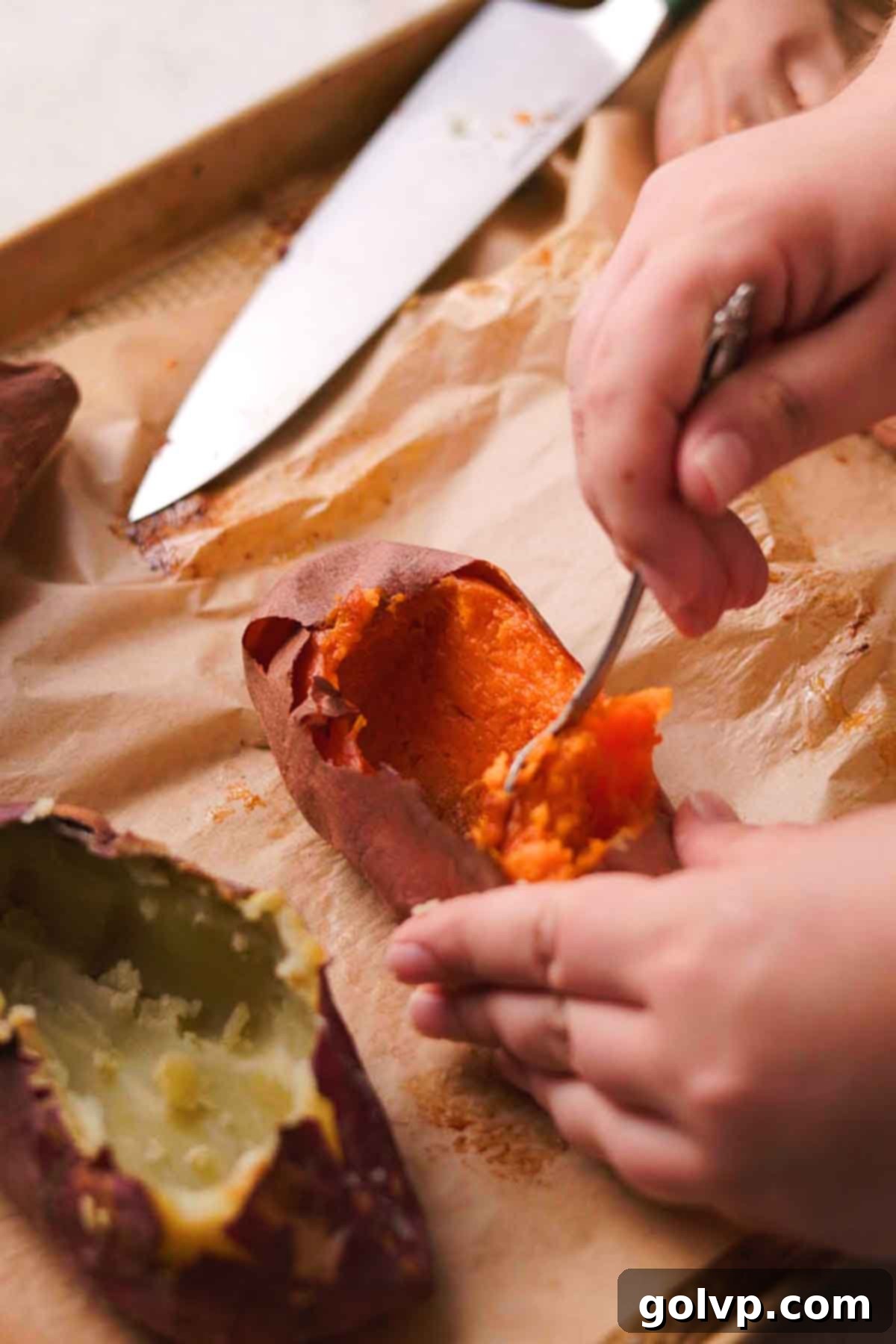 A cook carefully hollowing out a roasted sweet potato, creating a natural bowl for the crème brûlée.