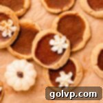 Top view of pumpkin pie cookies with whipped cream swirls, showcasing their perfect mini pie shape and golden crusts.