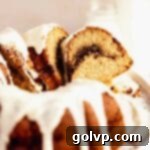 Cutting neat slices of a beautiful cinnamon bundt cake, revealing its appealing spiral swirl of gooey cinnamon sugar within.