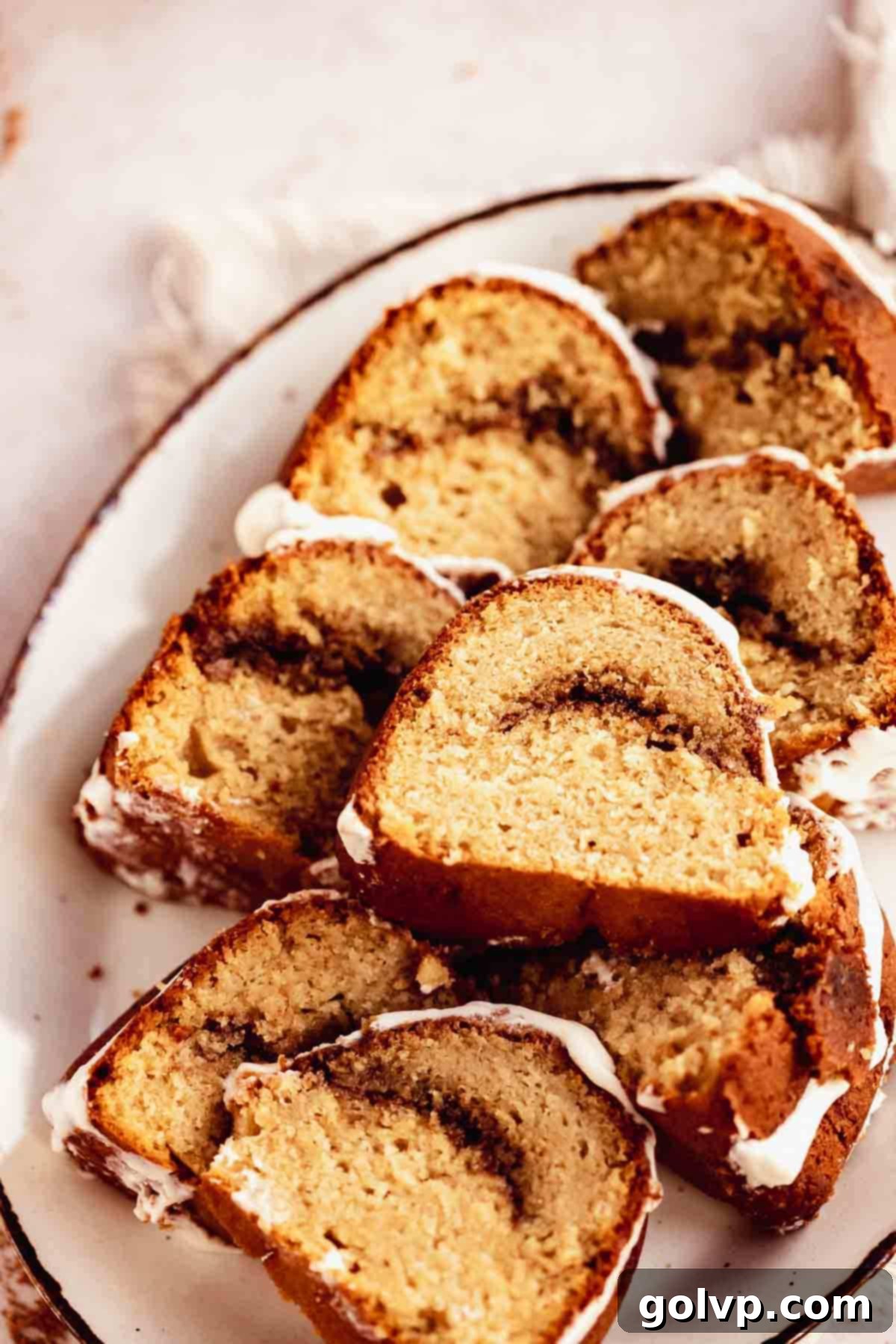 A plate featuring perfectly sliced pieces of cinnamon swirl bundt cake, showcasing the moist crumb, rich cinnamon swirl, and creamy glaze.