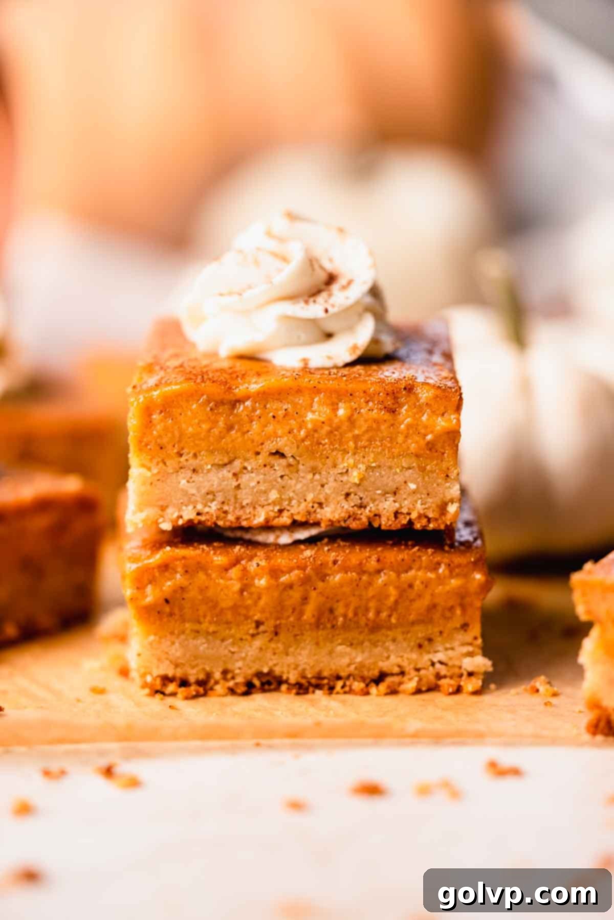 A stack of perfectly portioned brown butter pumpkin pie bars, featuring their distinct golden crust layers and rich filling, ready for sharing.