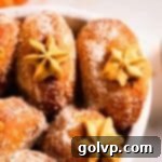 Pumpkin donuts with a visible piped custard filling peeking out, beautifully arranged in a casserole dish, ready to serve.