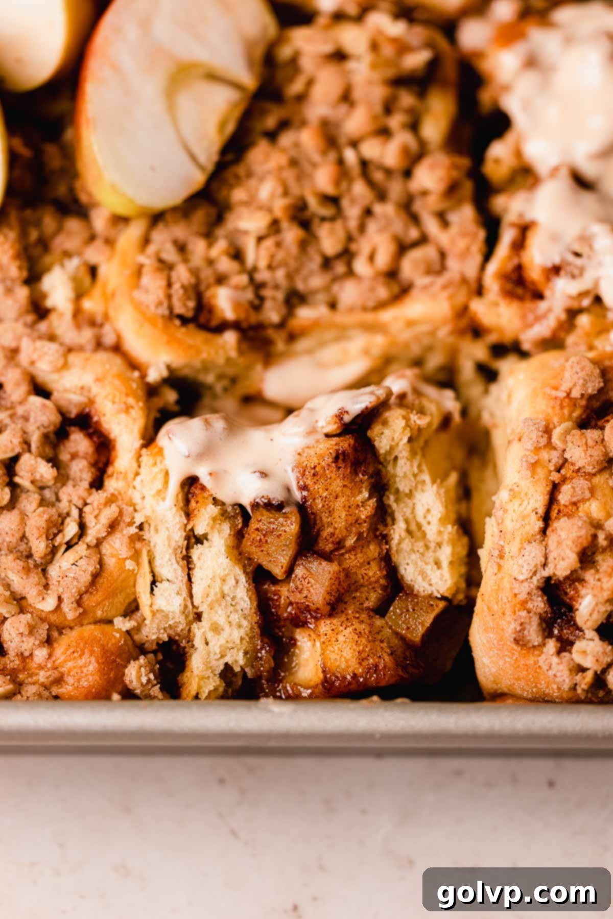 A beautiful cross-section of a gooey salted caramel apple cinnamon roll, revealing the rich spiced apple filling and tender spiral dough within.
