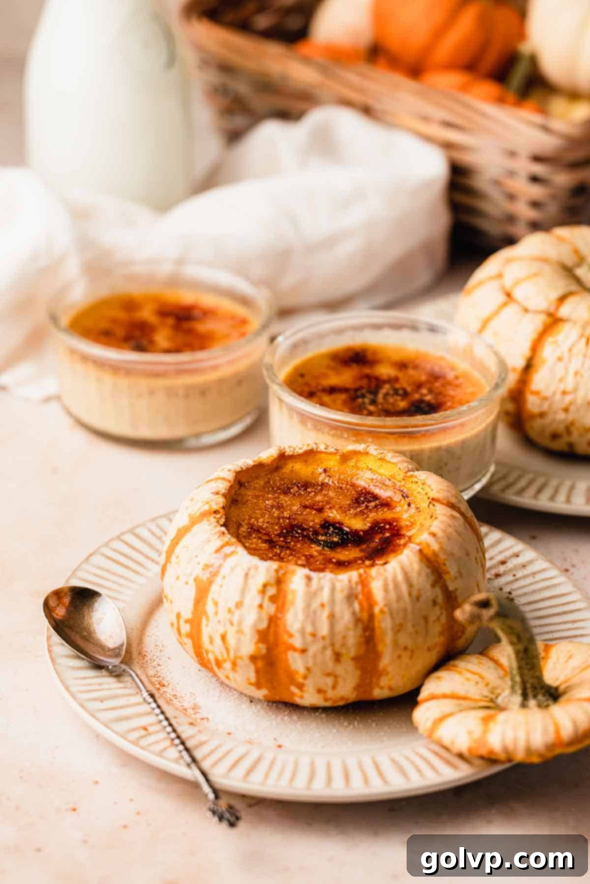 An inviting tablescape featuring pumpkin crème brûlées served both in charming mini pumpkins and classic ramekins, alongside a glass milk pitcher, creating a rustic and elegant holiday ambiance.