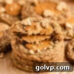 A stack of pumpkin cheesecake filled cookies, showcasing their creamy centers and delicious texture, neatly arranged on parchment paper.