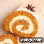 A beautifully sliced pumpkin cake roll revealing its perfect spiral of cake and creamy cheesecake filling, elegantly garnished with star anise.