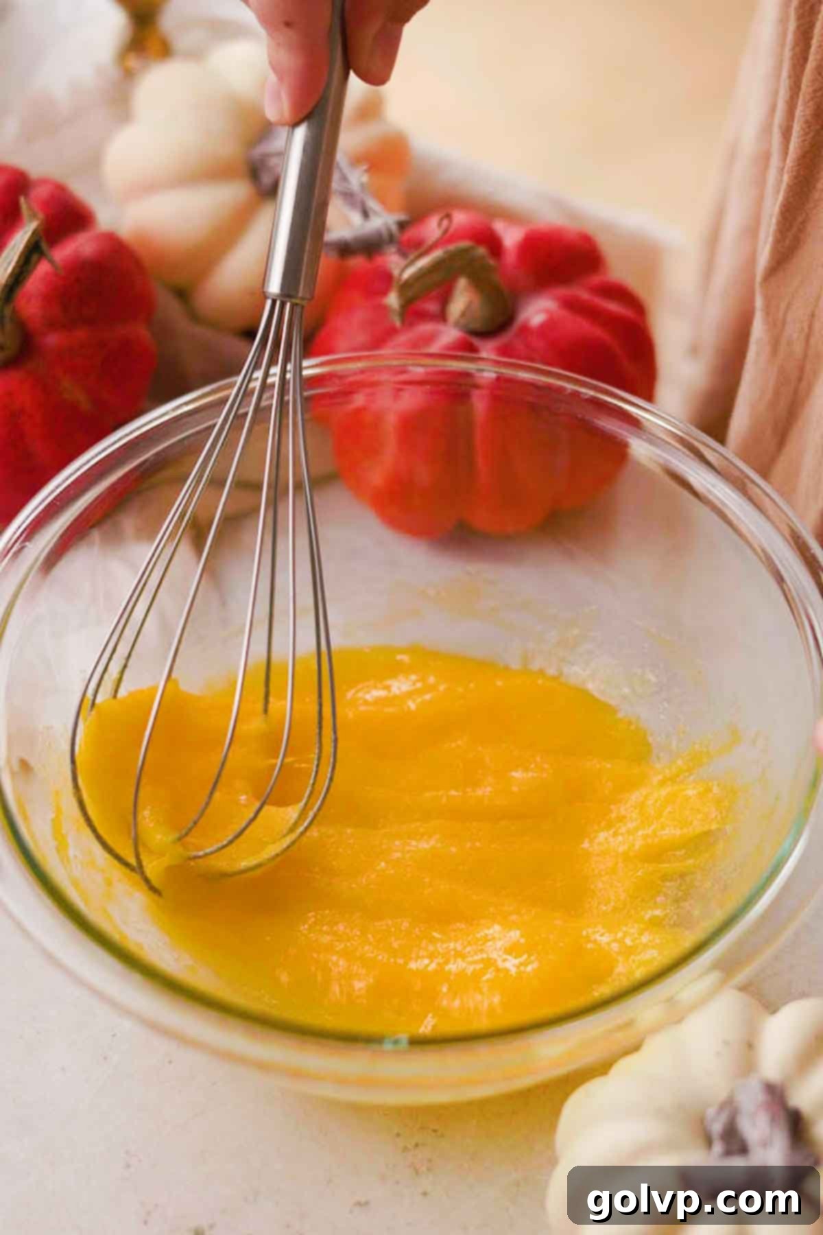 Whisking egg yolks, a whole egg, and sugar in a heat-safe bowl, preparing for the creamy pumpkin tiramisu filling.