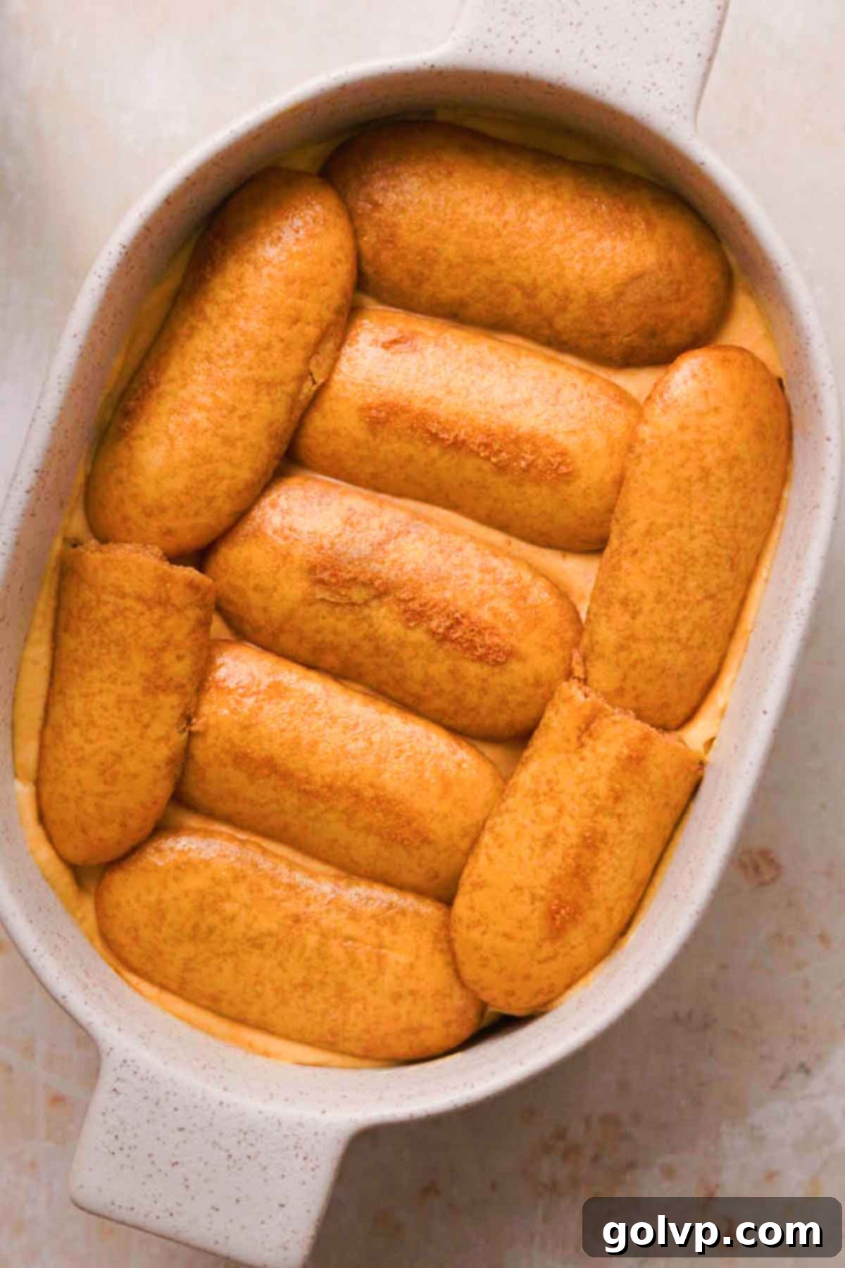 Layering coffee-soaked ladyfingers in a serving dish
