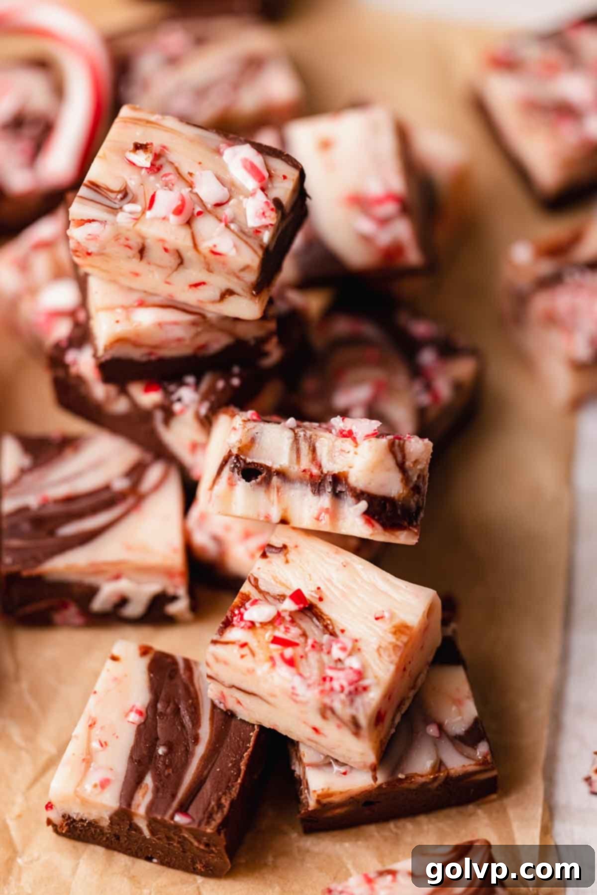 Indulgent Peppermint Fudge 2 A delectable piece of Peppermint Swirl Fudge with a bite taken out, showcasing the distinct layers of white and dark chocolate and crushed peppermint candies on top.