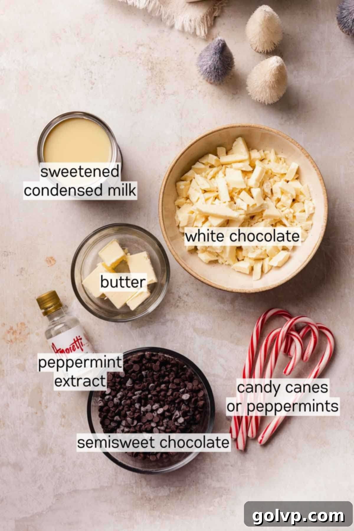 Indulgent Peppermint Fudge 4 Bowls of key ingredients for peppermint fudge: white chocolate, semisweet chocolate, butter, sweetened condensed milk, peppermint extract, and crushed candy canes.