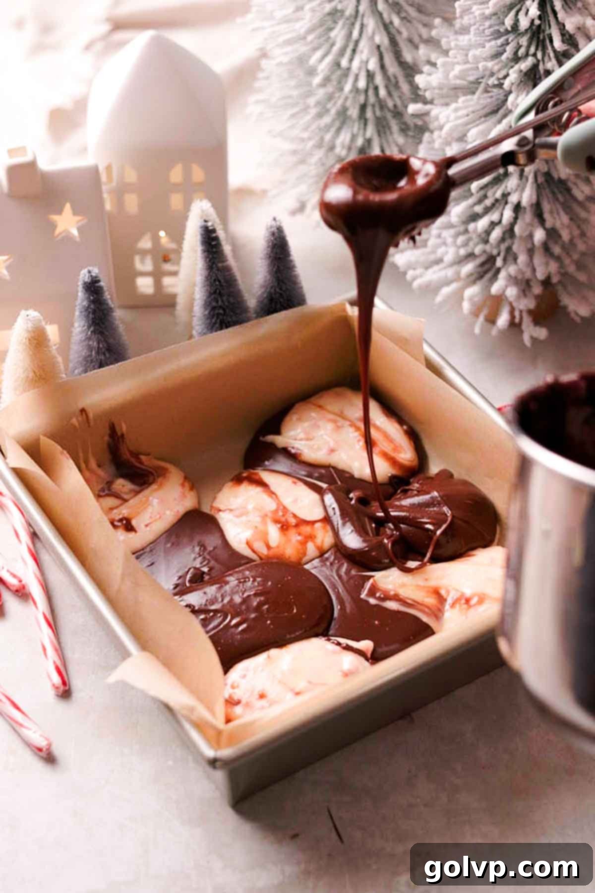 Indulgent Peppermint Fudge 7 Alternating dollops of dark and white peppermint fudge mixture in a parchment-lined square pan, ready for swirling.