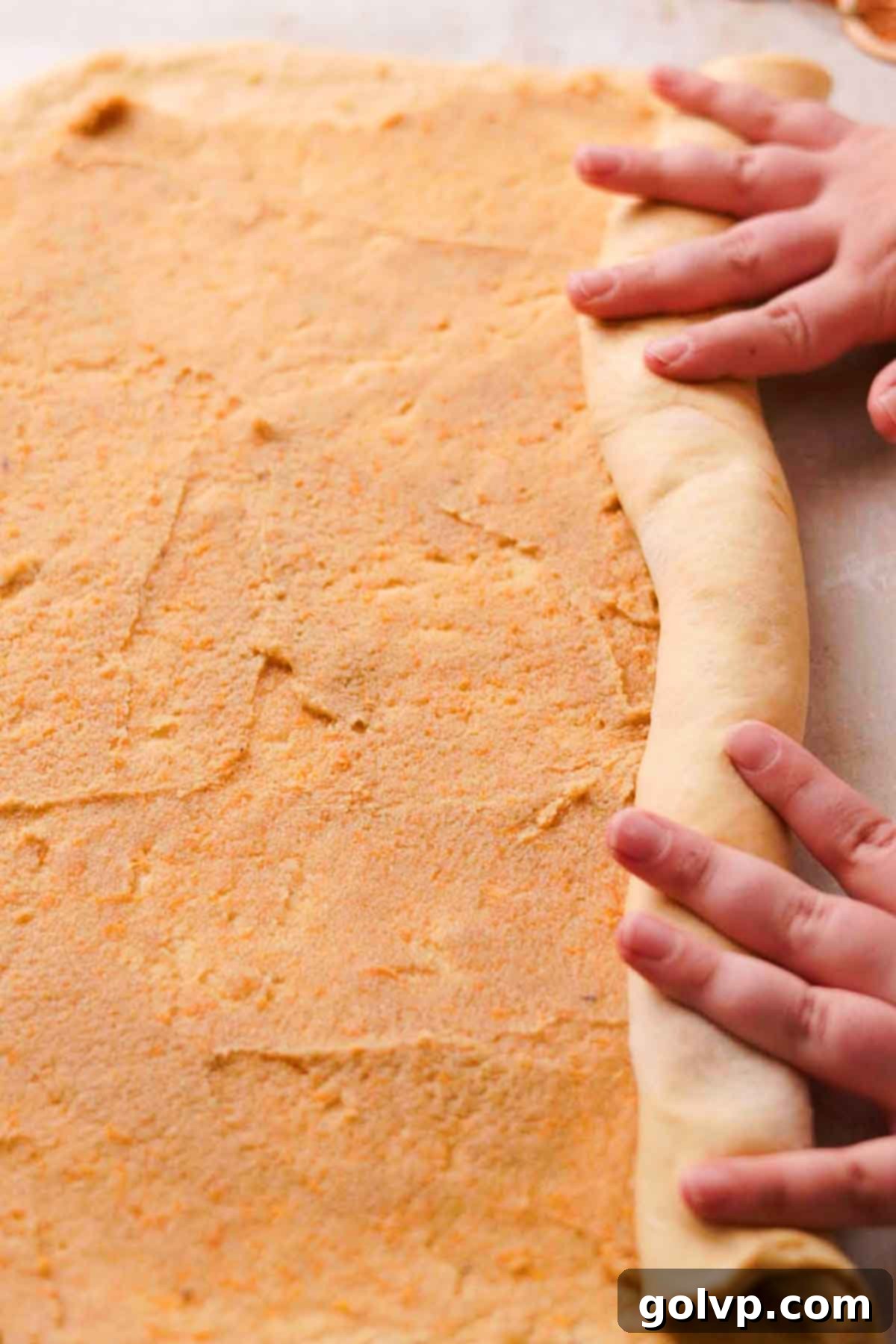 rolling dough into log with orange filling spread on it