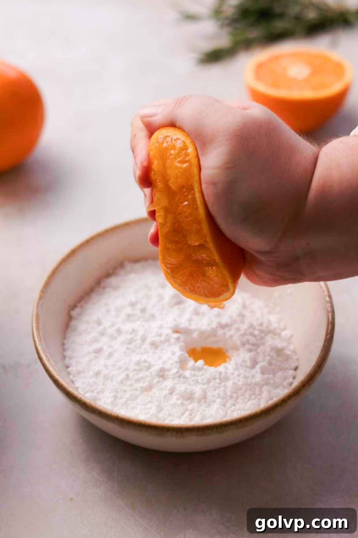 squeezing fresh orange juice into powdered sugar for glaze