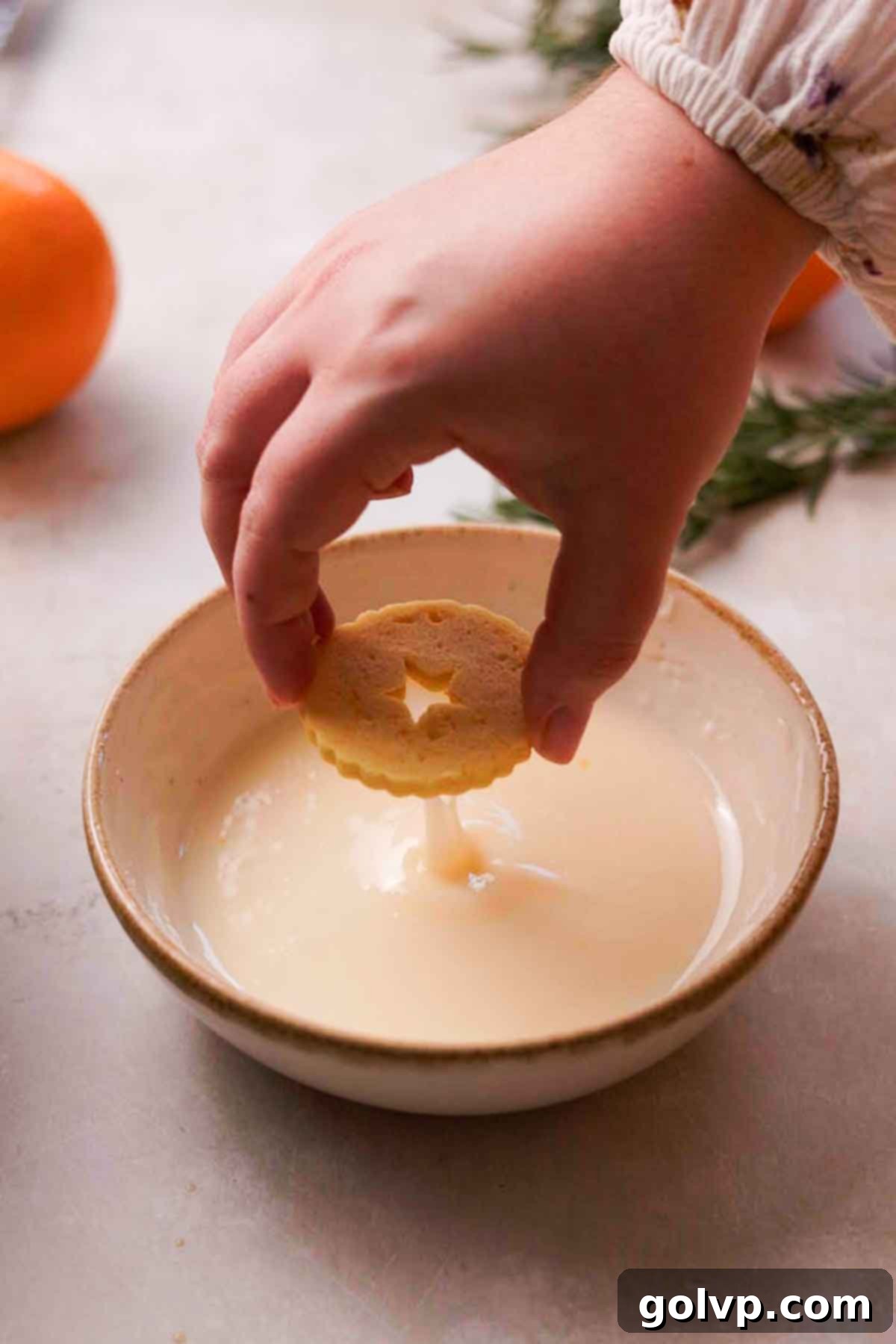 dipping shortbread cookies into orange glaze