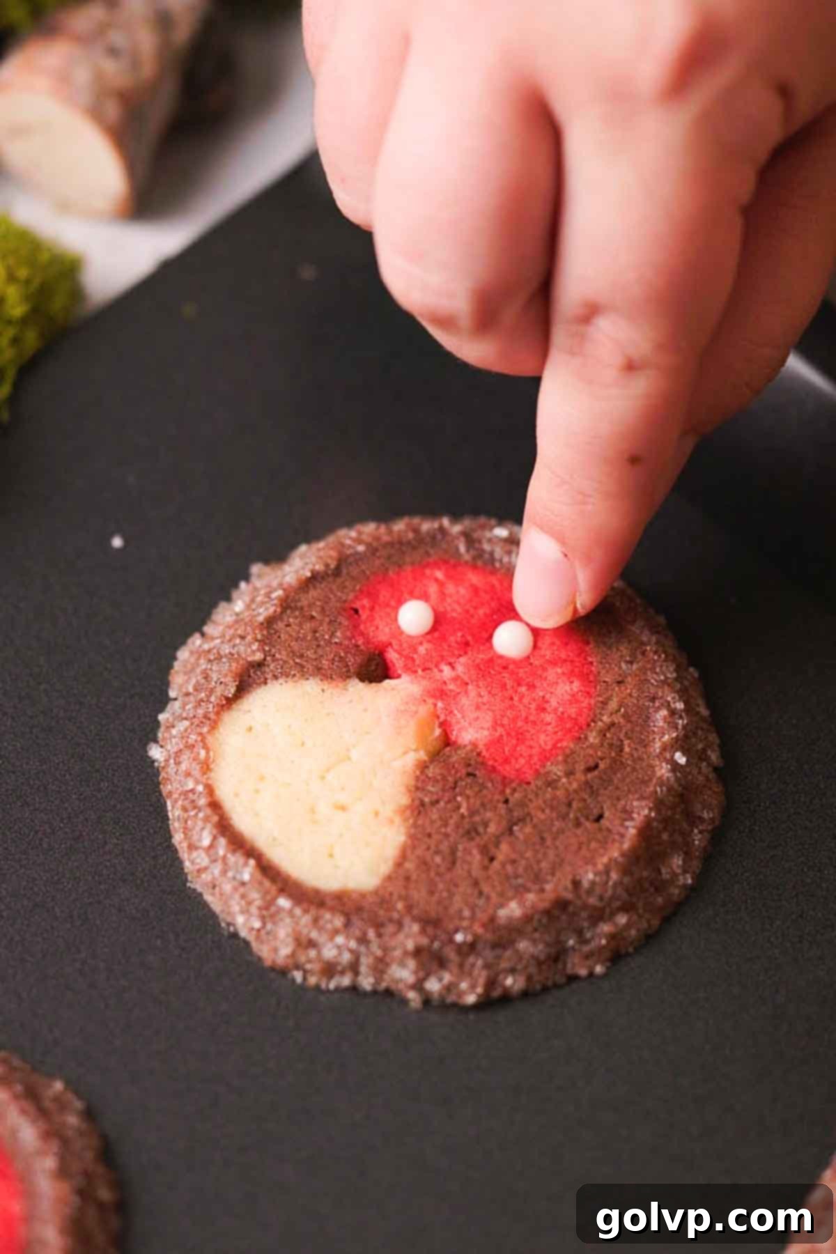 pressing white sprinkles onto freshly baked mushroom cookie tops