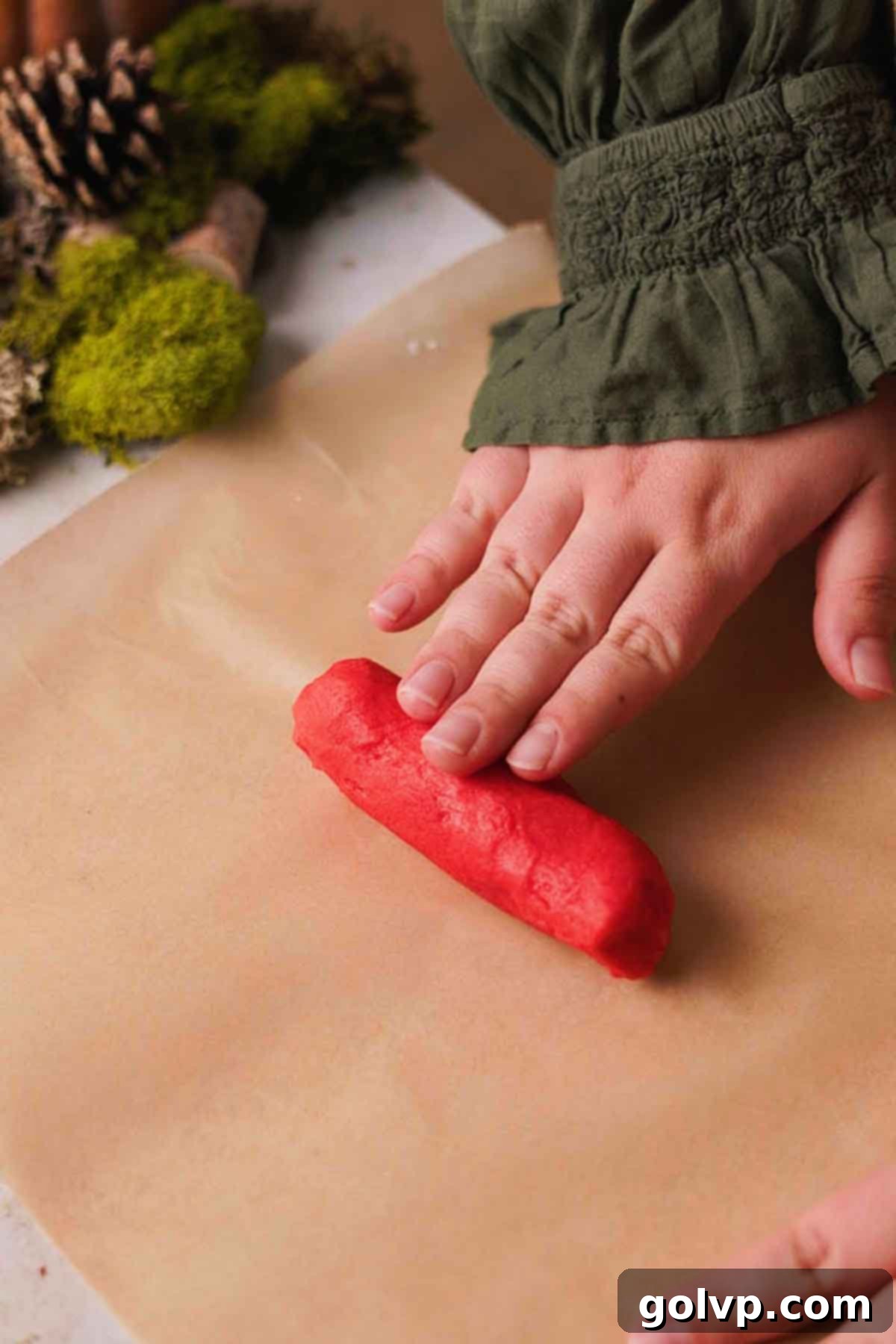 rolling red colored dough into a short thick log for the mushroom cap