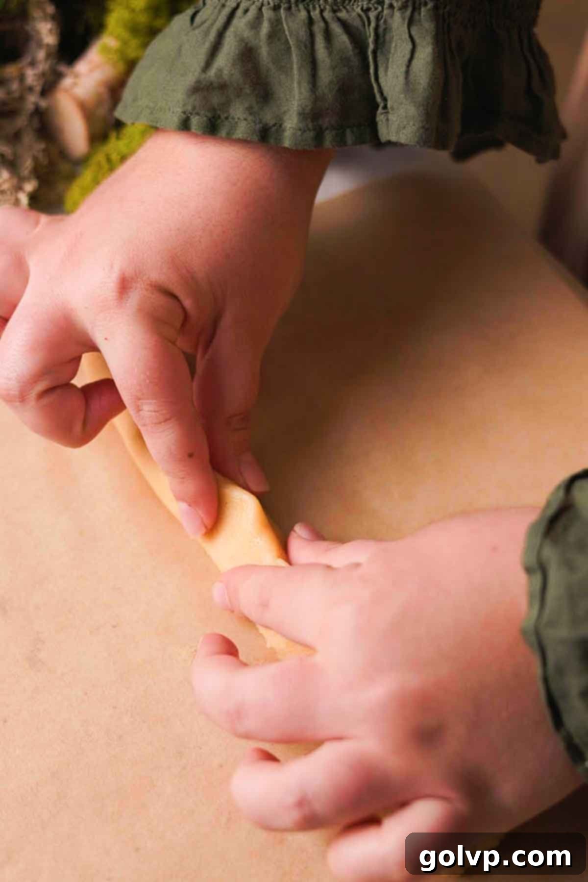 pinching white dough log into a triangle shape for the mushroom stem