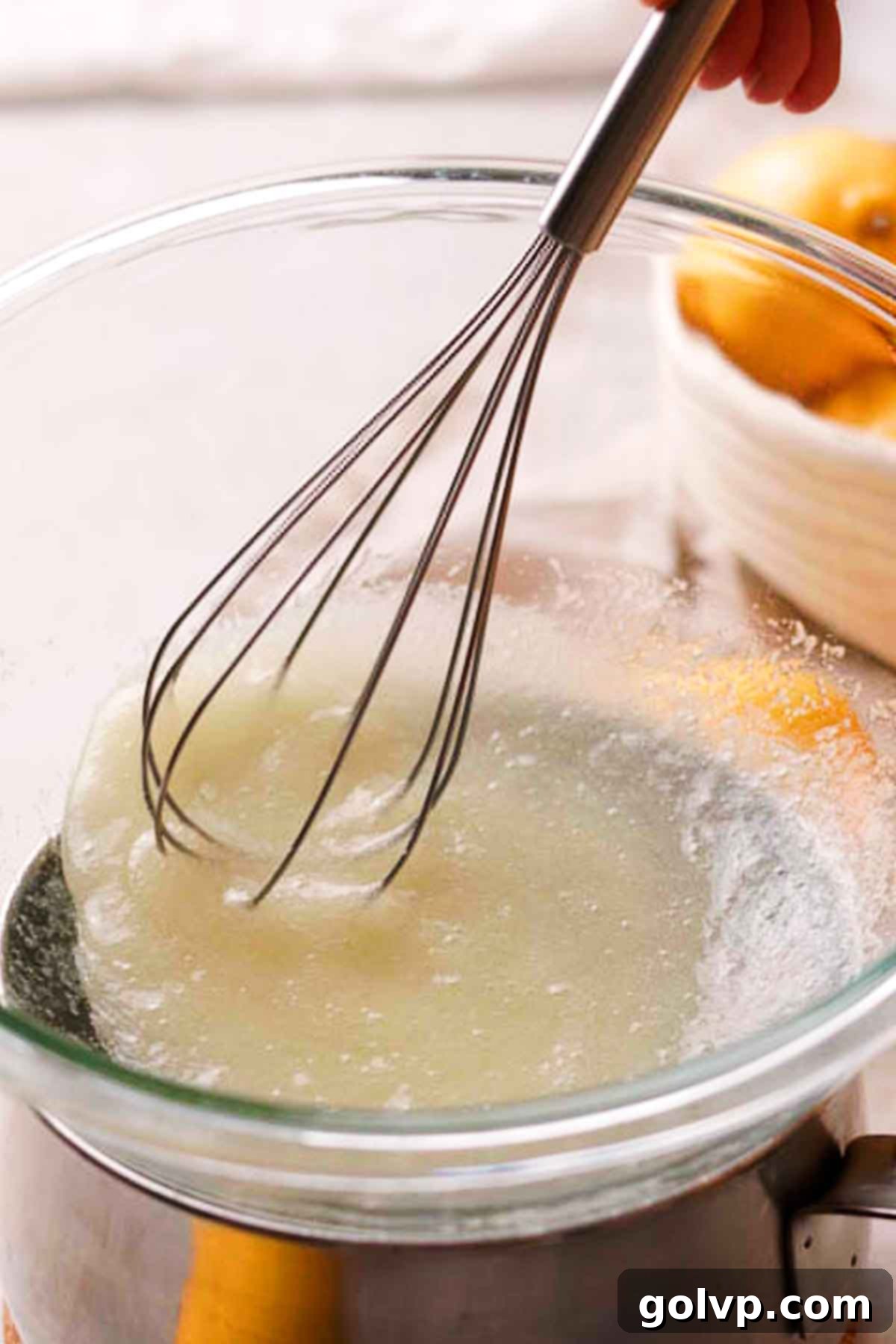 Whisking egg whites, granulated sugar, salt, and cream of tartar in a heat-safe bowl over simmering water for Swiss meringue