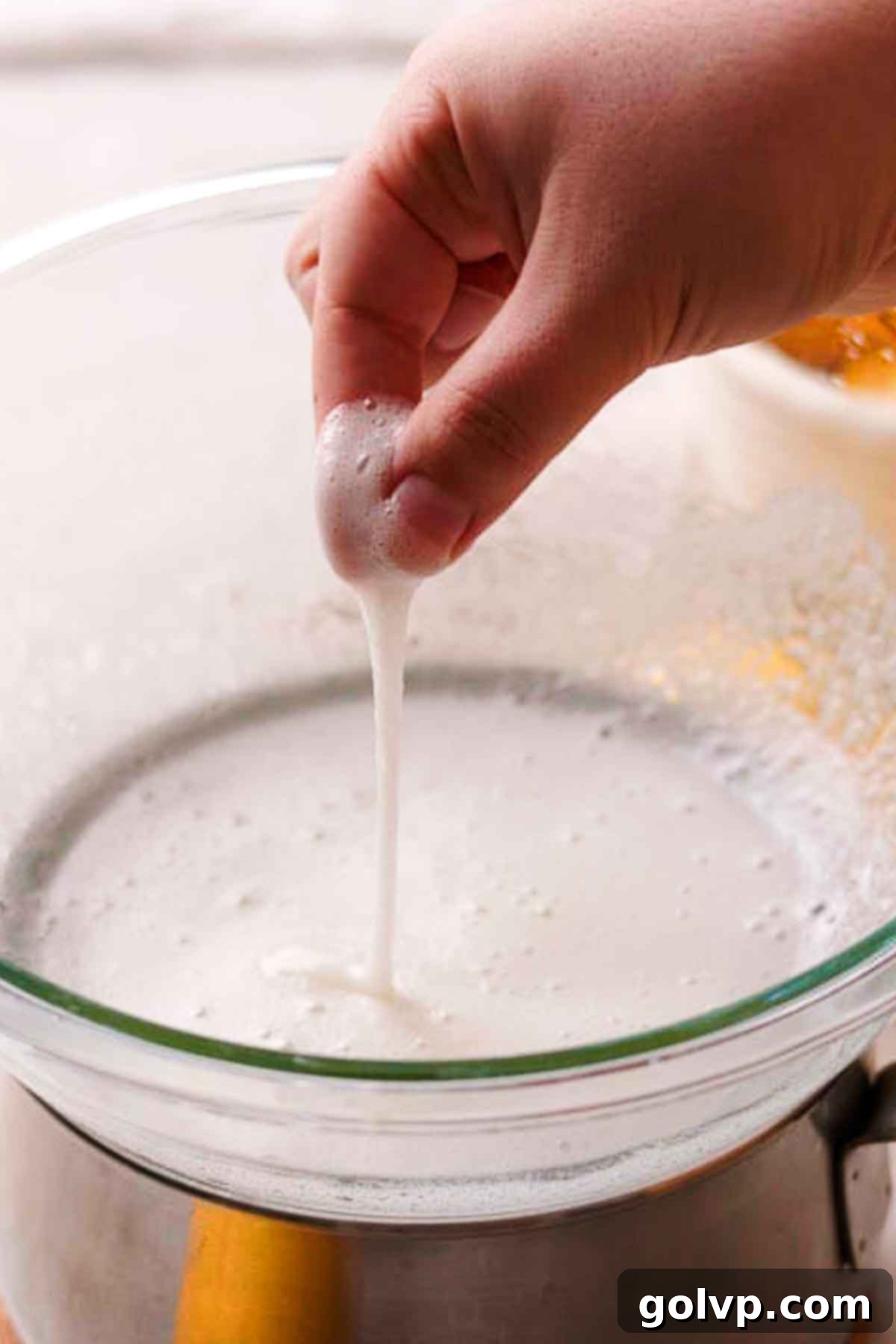 Rubbing Swiss meringue mixture between fingers to check for dissolved sugar crystals before whipping