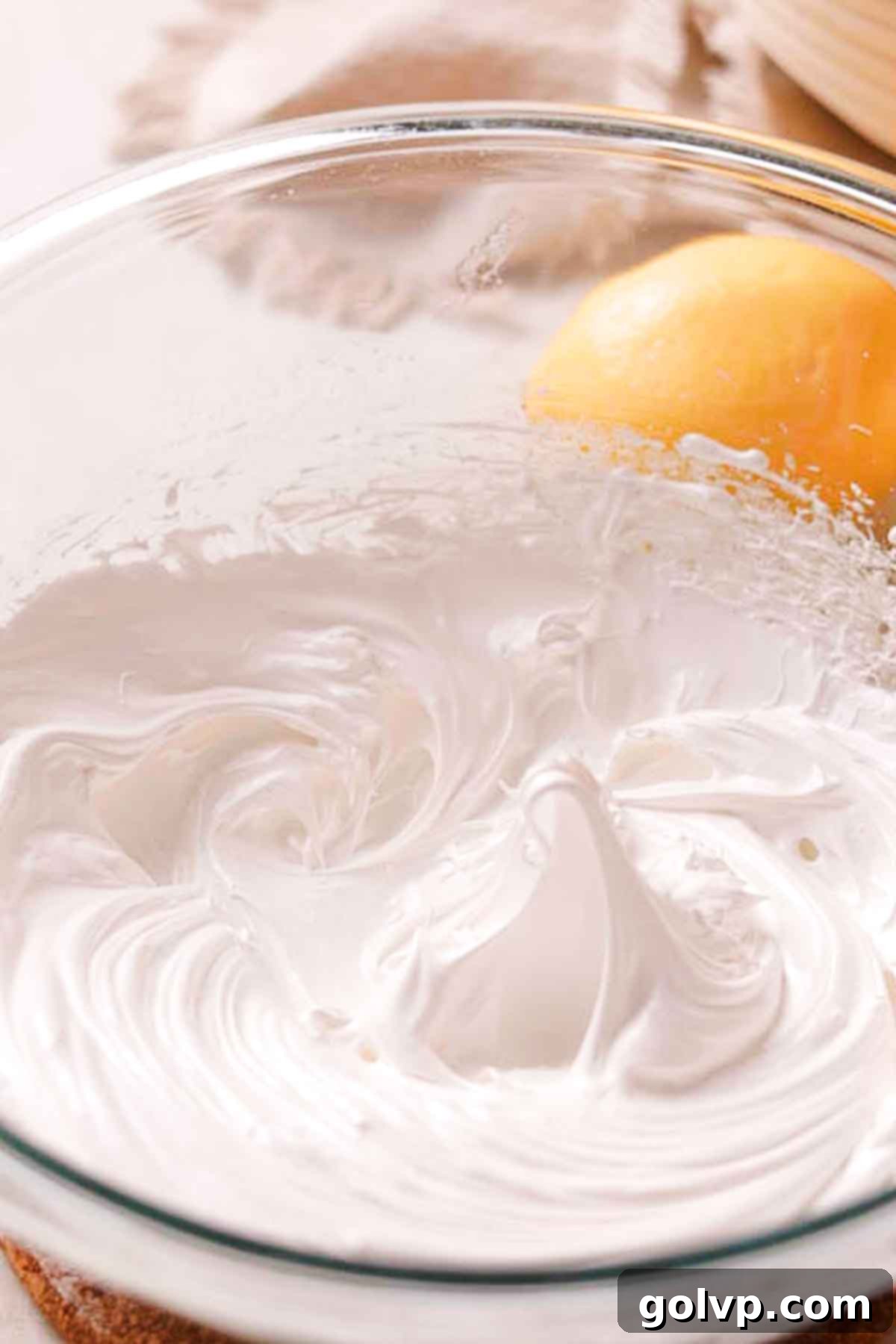 Perfectly whipped stiff peaks of Swiss meringue in a glass bowl, ready for piping