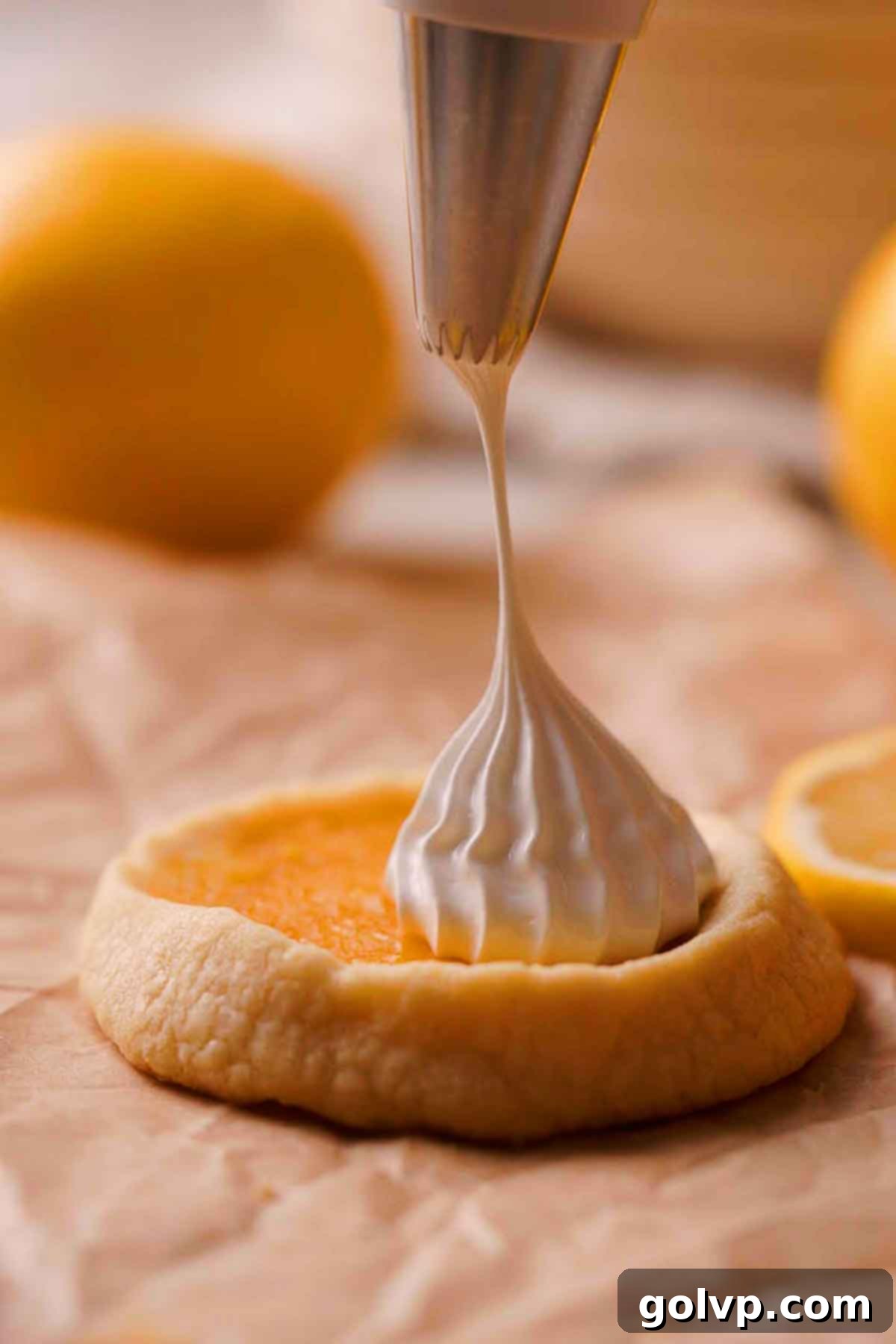 Piping dollops of fluffy Swiss meringue onto baked lemon-filled cookies using a star tip