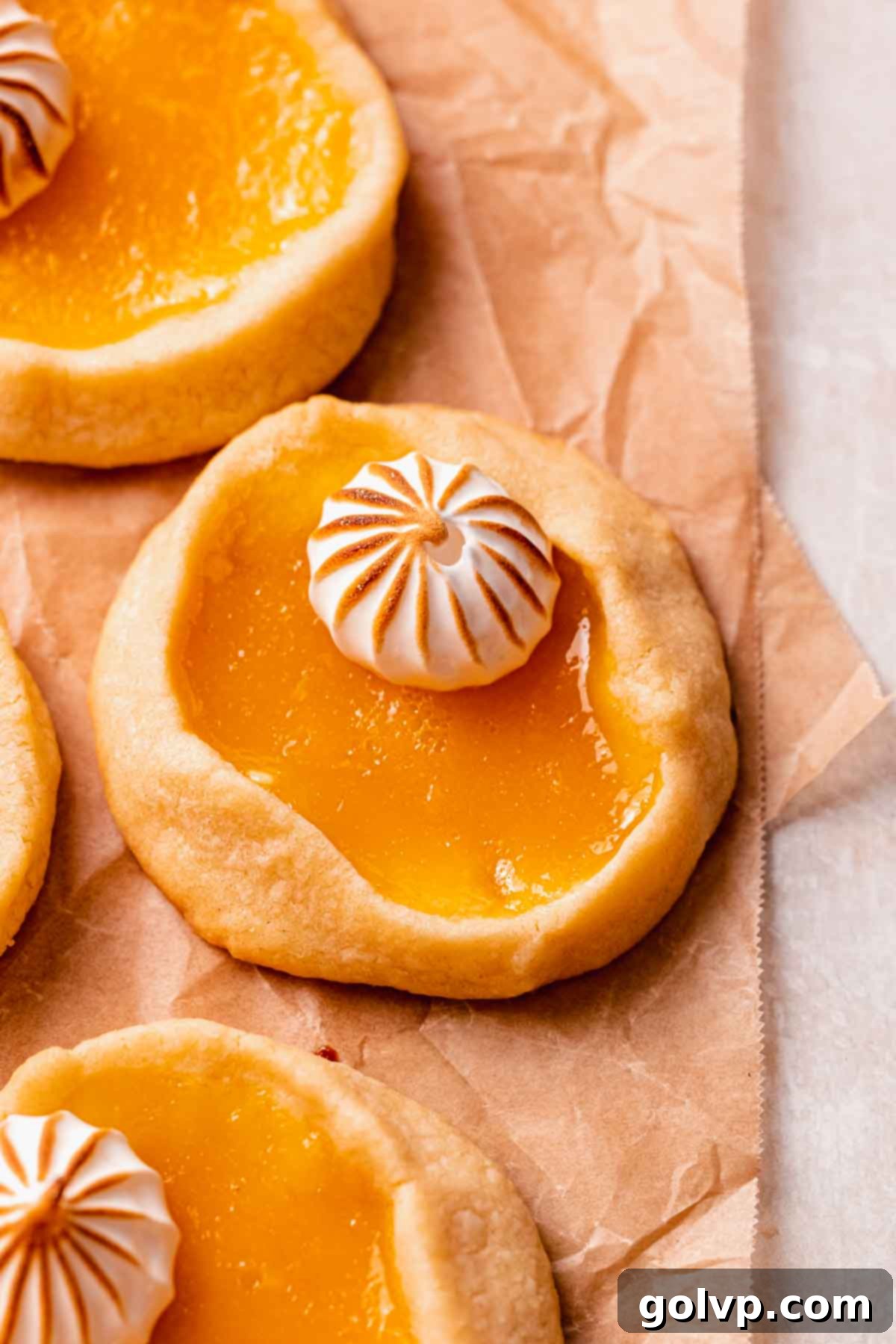 A close-up view of a single lemon meringue pie cookie, highlighting the crisp shortbread, glossy lemon filling, and toasted meringue