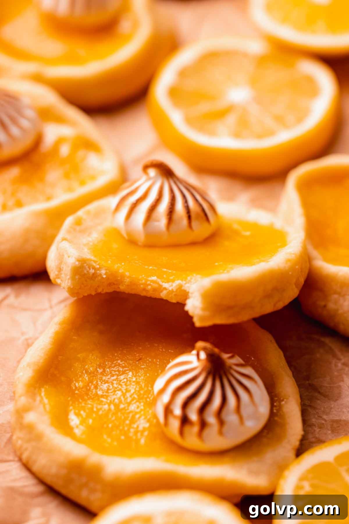 A partially eaten lemon meringue pie cookie showing the crisp shortbread base, creamy lemon filling, and toasted meringue top