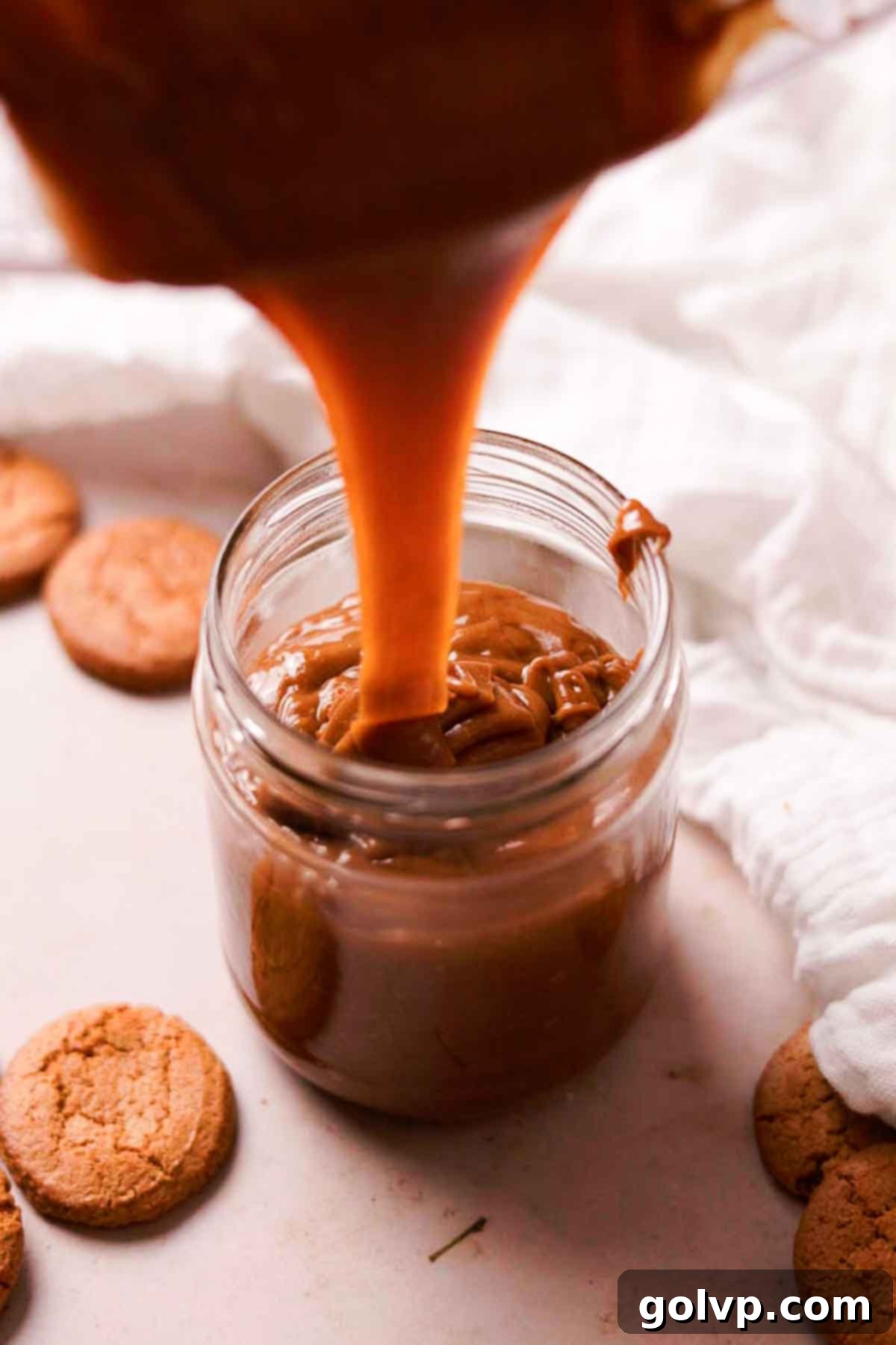 pouring warm homemade cookie butter in a glass jar