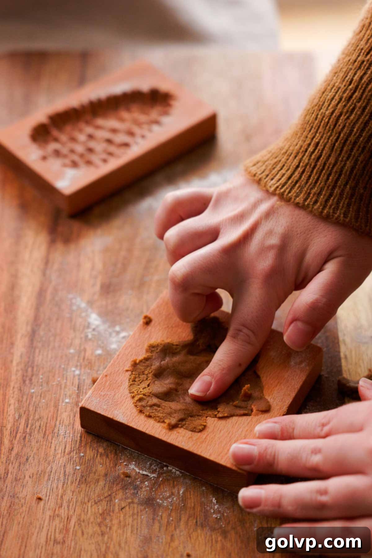 pressing gingerbread cookie dough into wooden mold