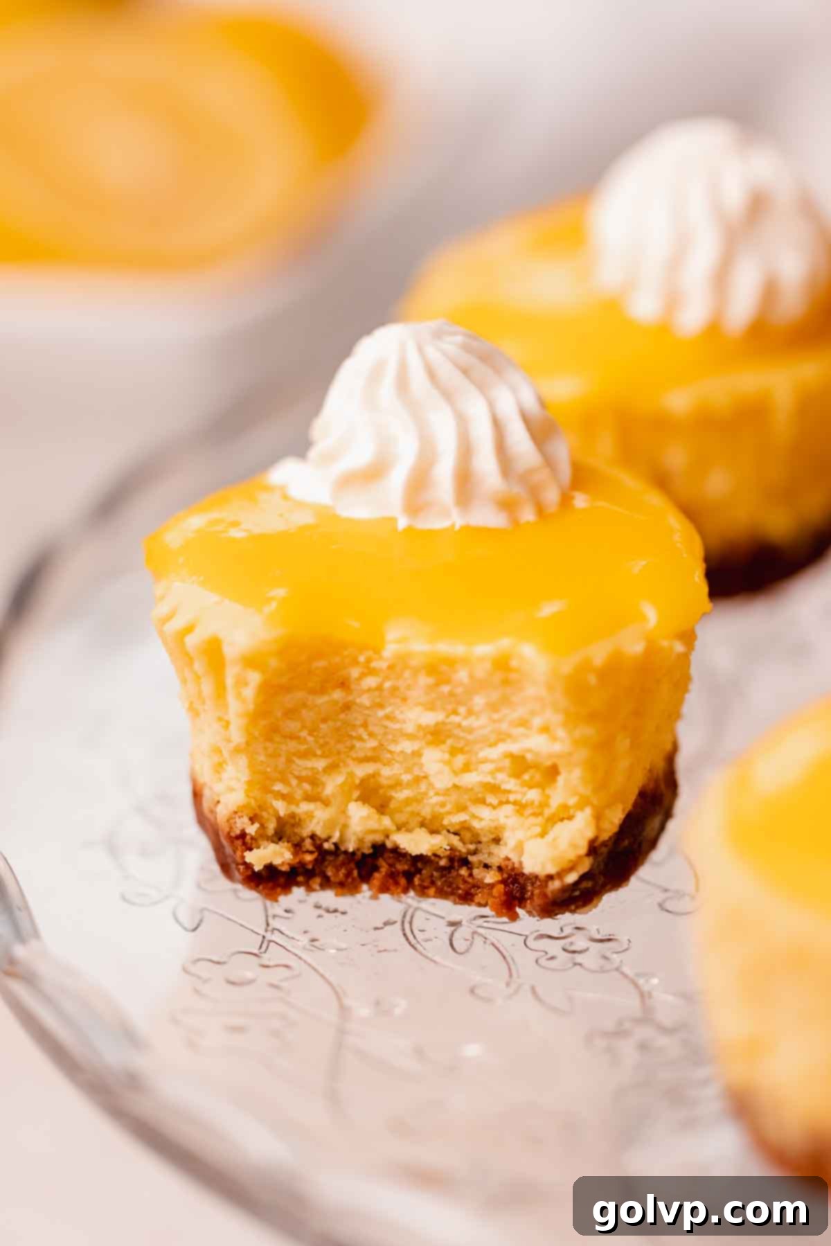 Sunshine Lemon Cheesecakes 3 bitten lemon mini cheesecake showcasing layers of crust, filling, and topping