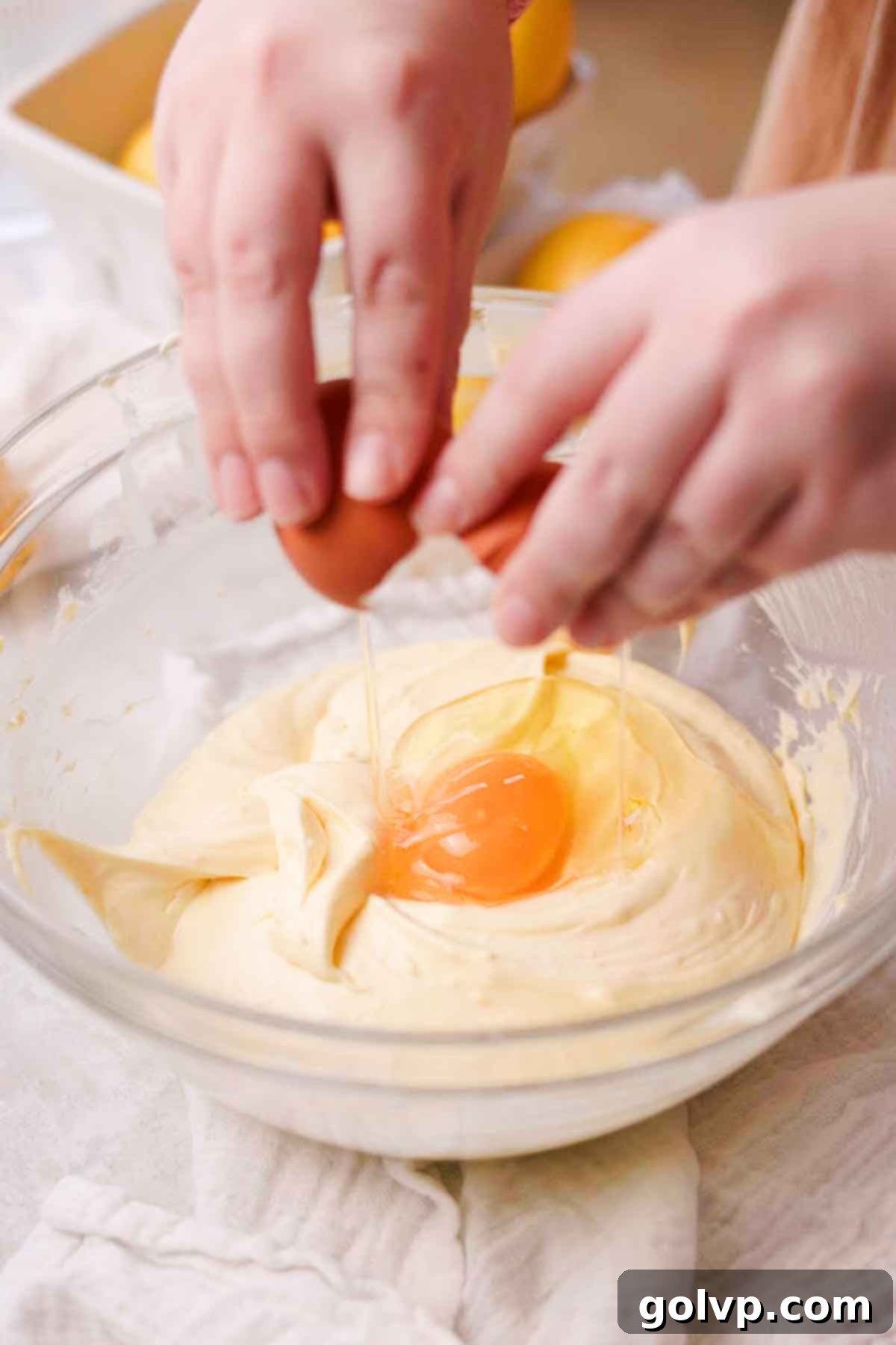 Sunshine Lemon Cheesecakes 9 breaking eggs into cheesecake batter