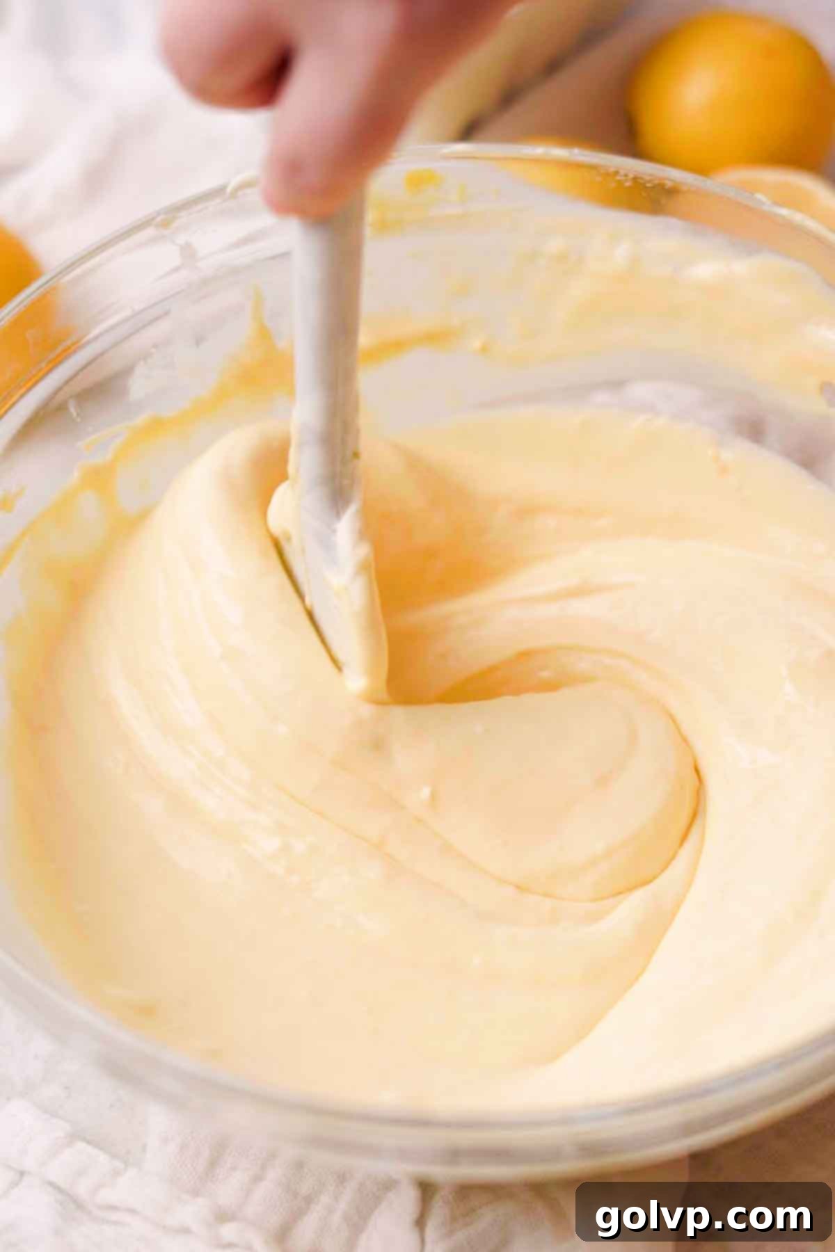 Sunshine Lemon Cheesecakes 10 stirring lemon cheesecake batter with spatula