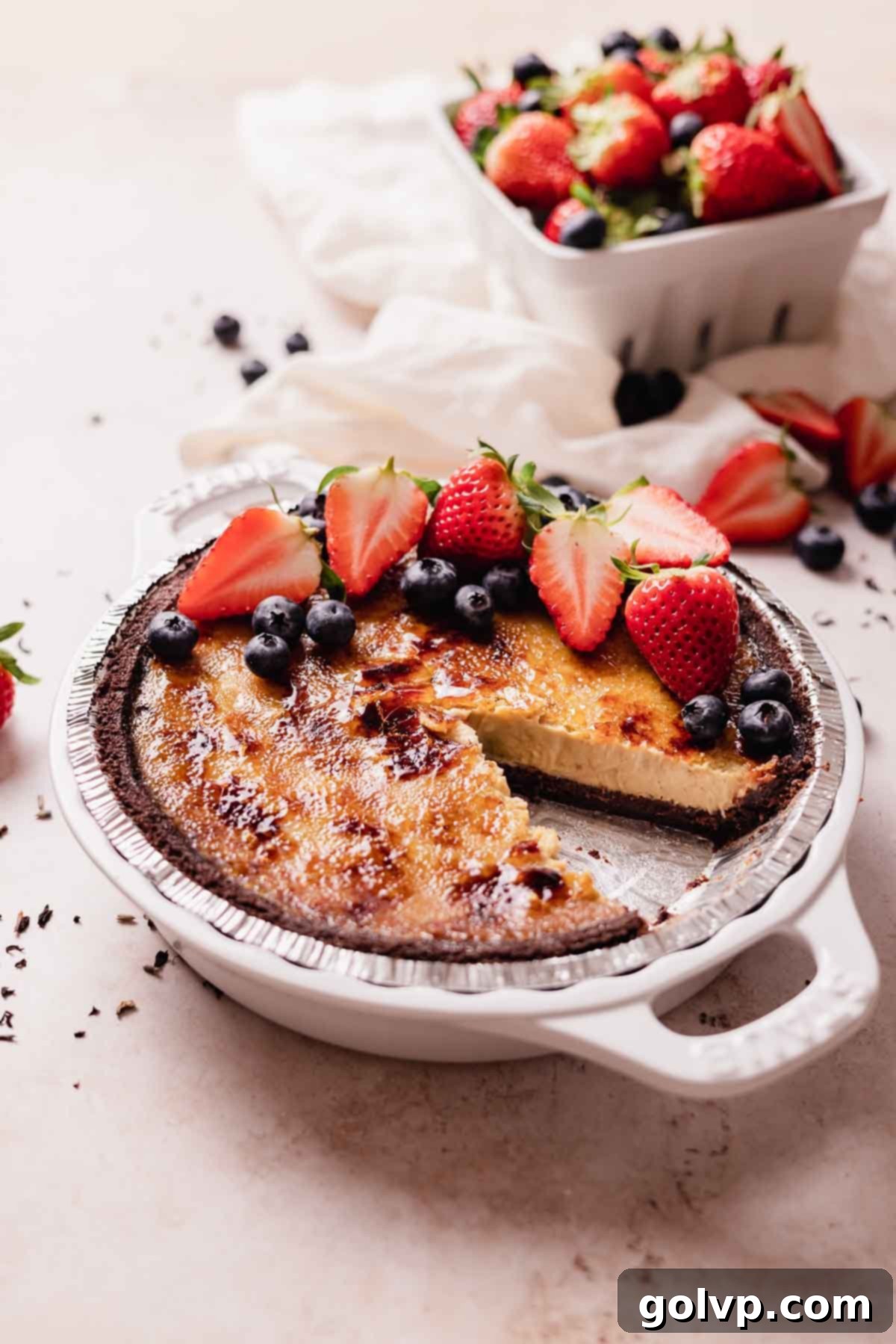 creme brulee pie with slice taken out of it and fresh berries