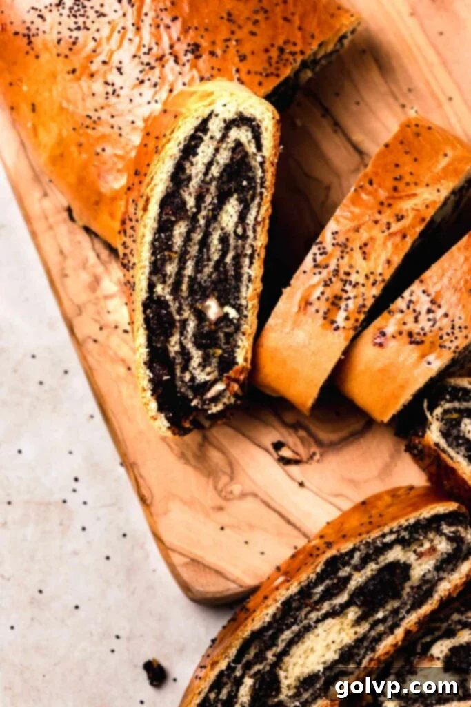 A perfectly sliced Ukrainian poppy seed roll on a wooden cutting board, showcasing its rich, swirled filling and tender, golden-brown crust.