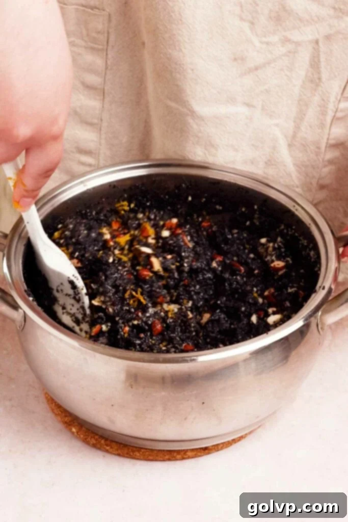 Adding various mix-ins like nuts, zest, and extracts to the cooked poppy seed filling in a bowl.