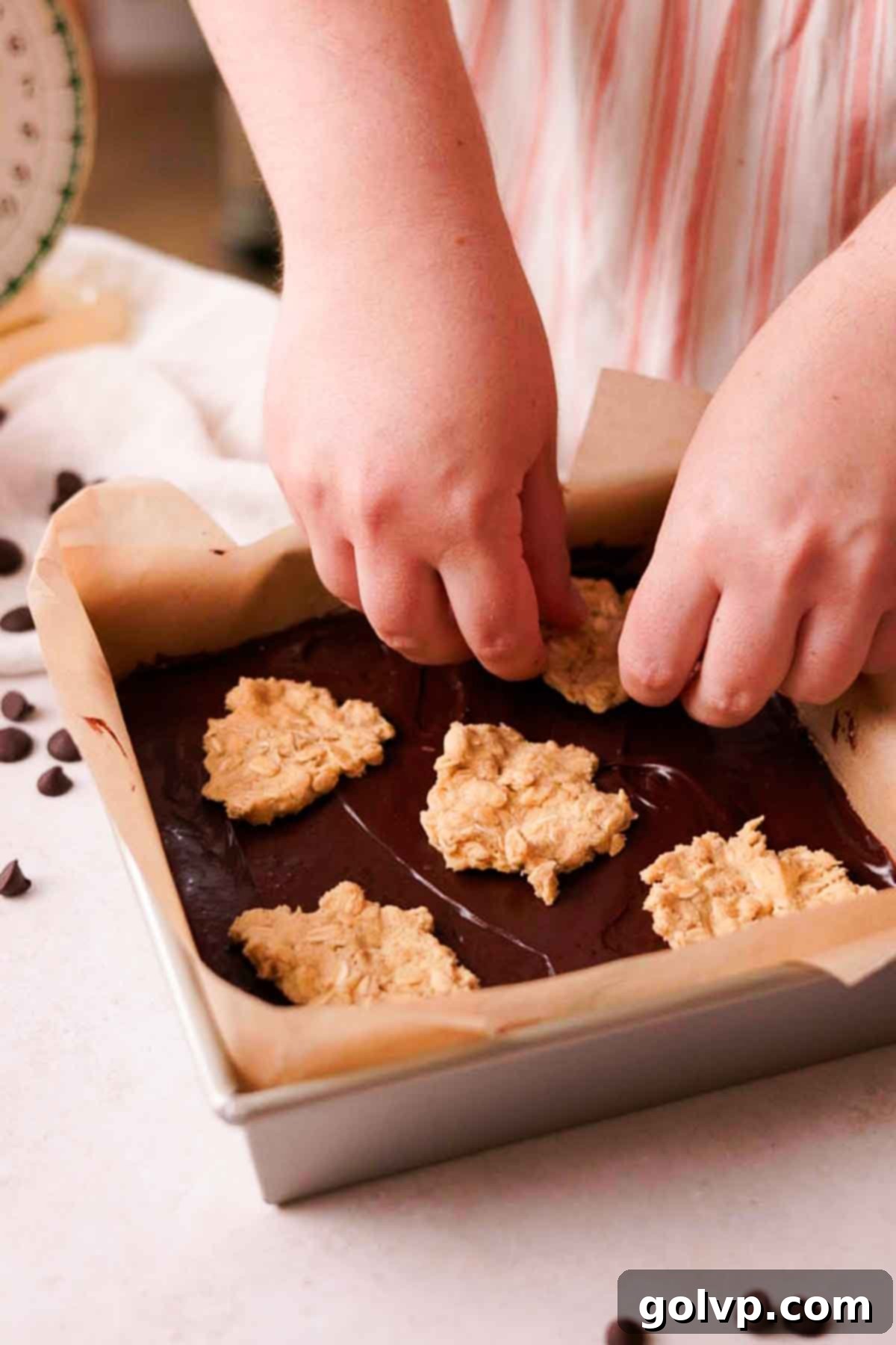 placing pieces of cookie dough on top of fudge in a pan