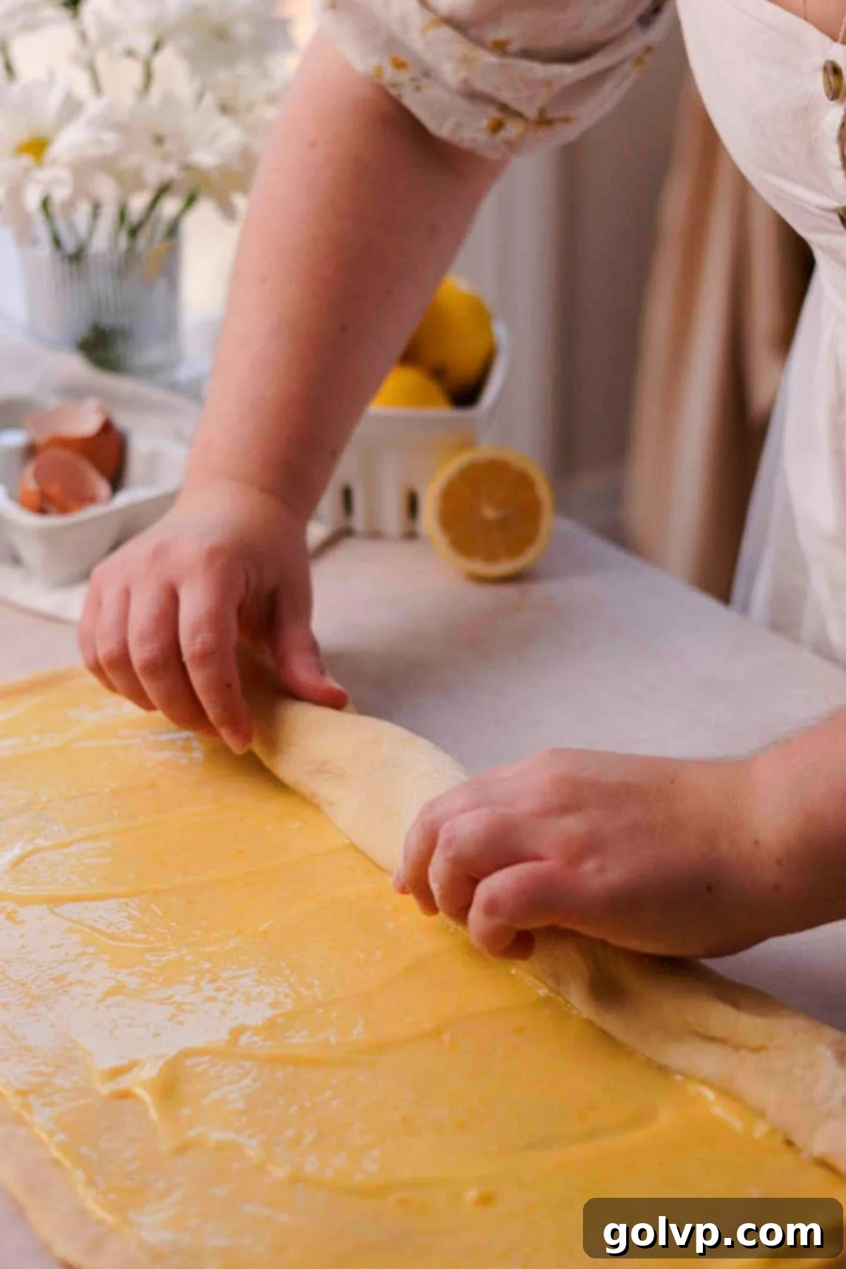 Using unflavored floss to cut the filled dough log into individual lemon rolls.