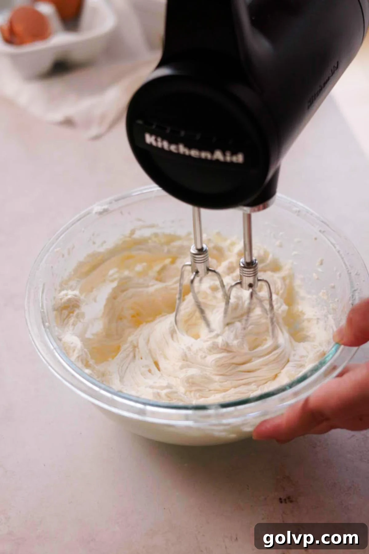Beating sour cream, vanilla, and lemon juice into the butter and sugar mixture for a fluffy frosting.
