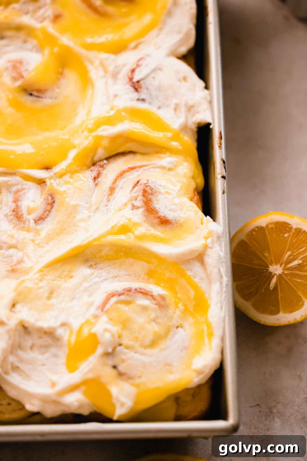 Close-up of lemon sweet rolls generously topped with creamy sour cream frosting and lemon curd swirls.
