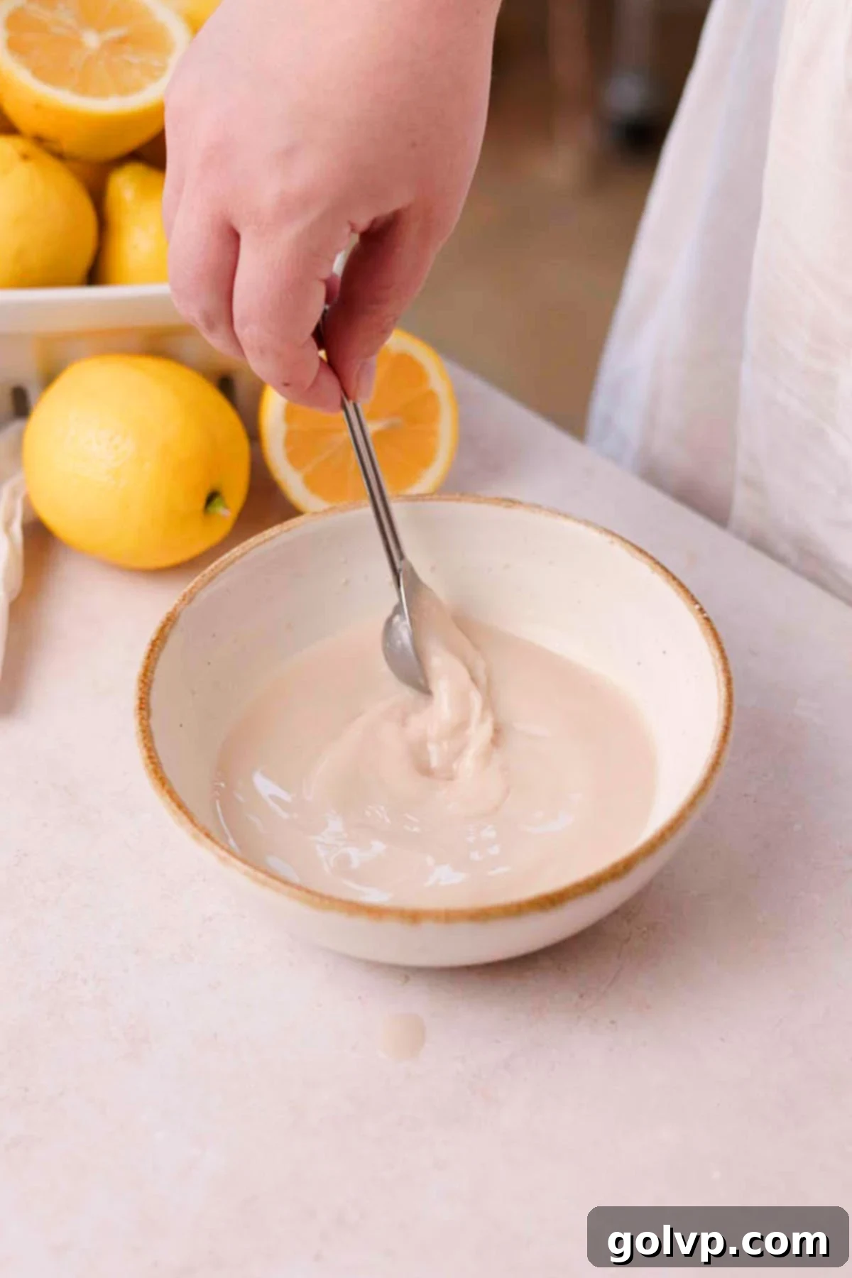 Mixing warm water, sugar, and yeast in a bowl to activate the yeast.