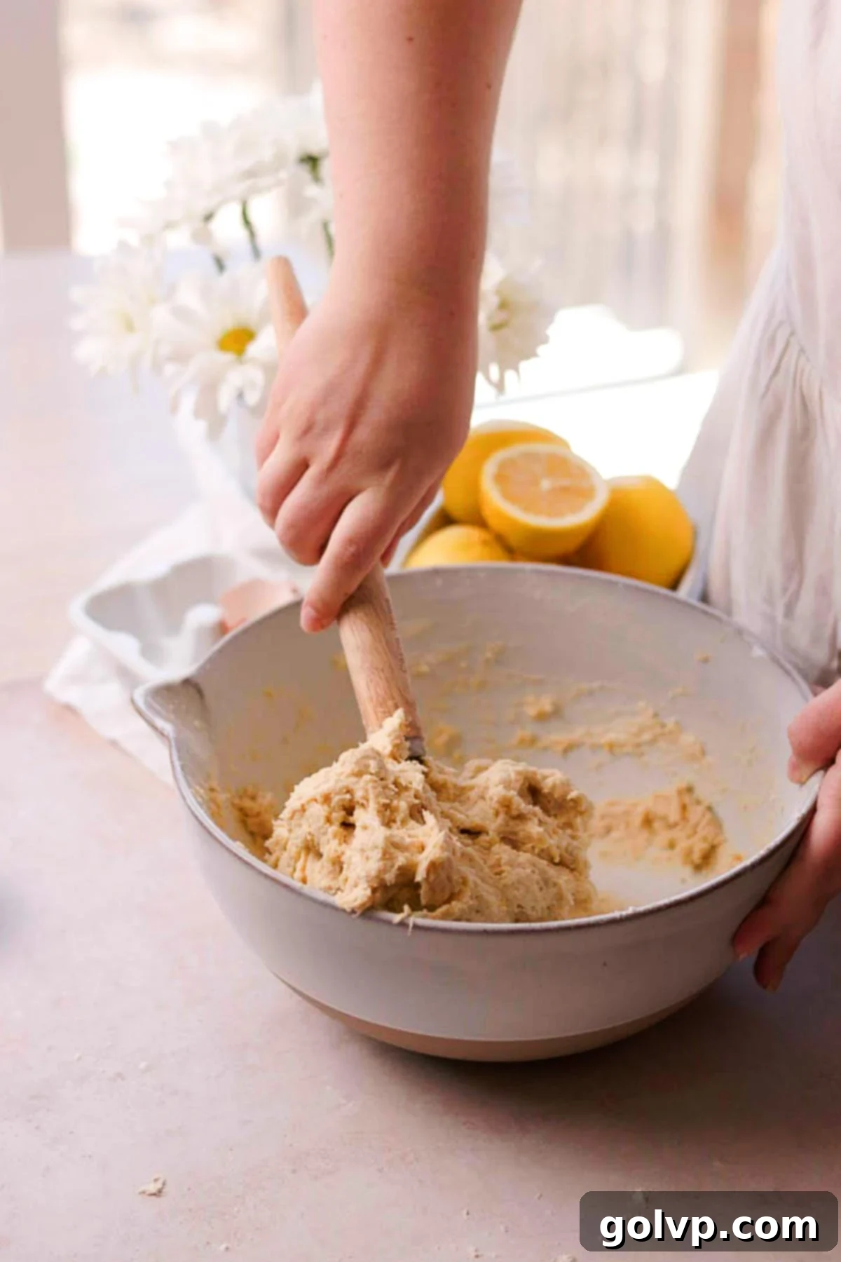 Mixing the no-knead lemon roll dough by hand with a Danish whisk in a large bowl.