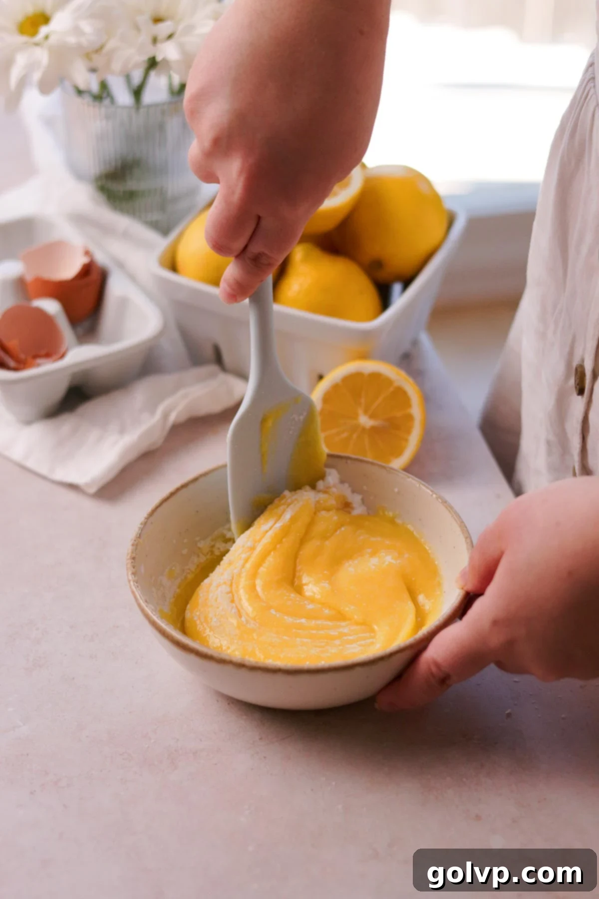 Stirring cornstarch into lemon curd in a bowl to thicken the filling.