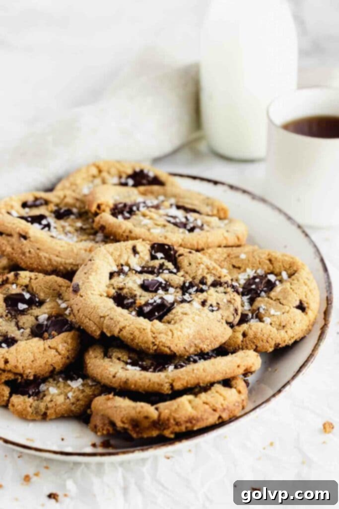 chocolate chip cookies stacked on plate with flaky salt