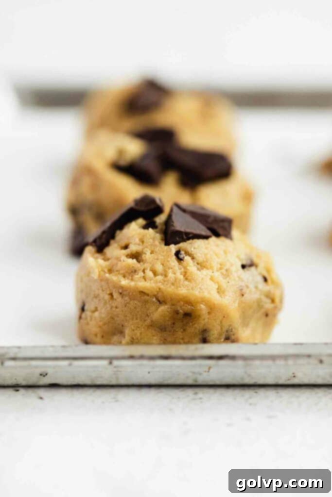 cookie dough balls with pieces of chocolate ready to bake