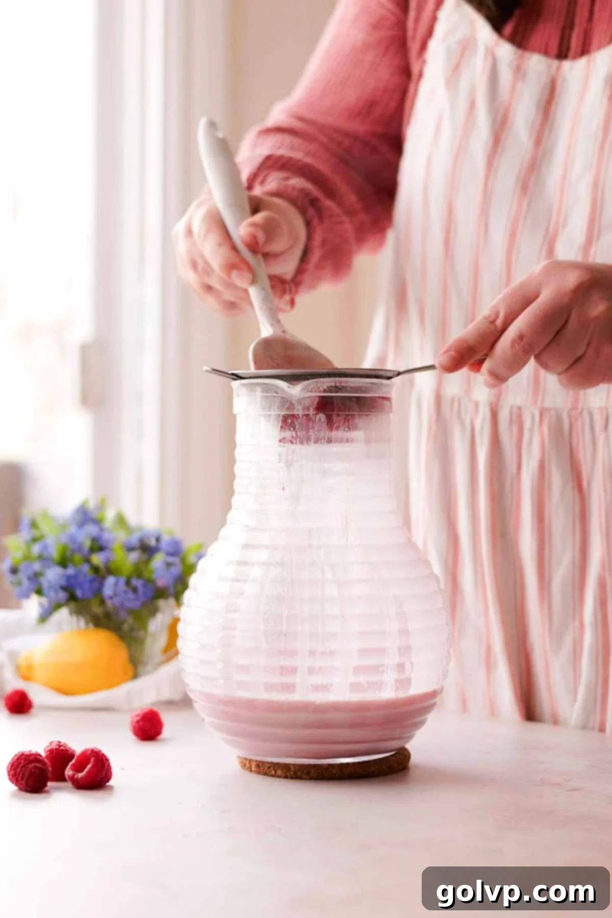 straining raspberry seeds out of raspberry posset