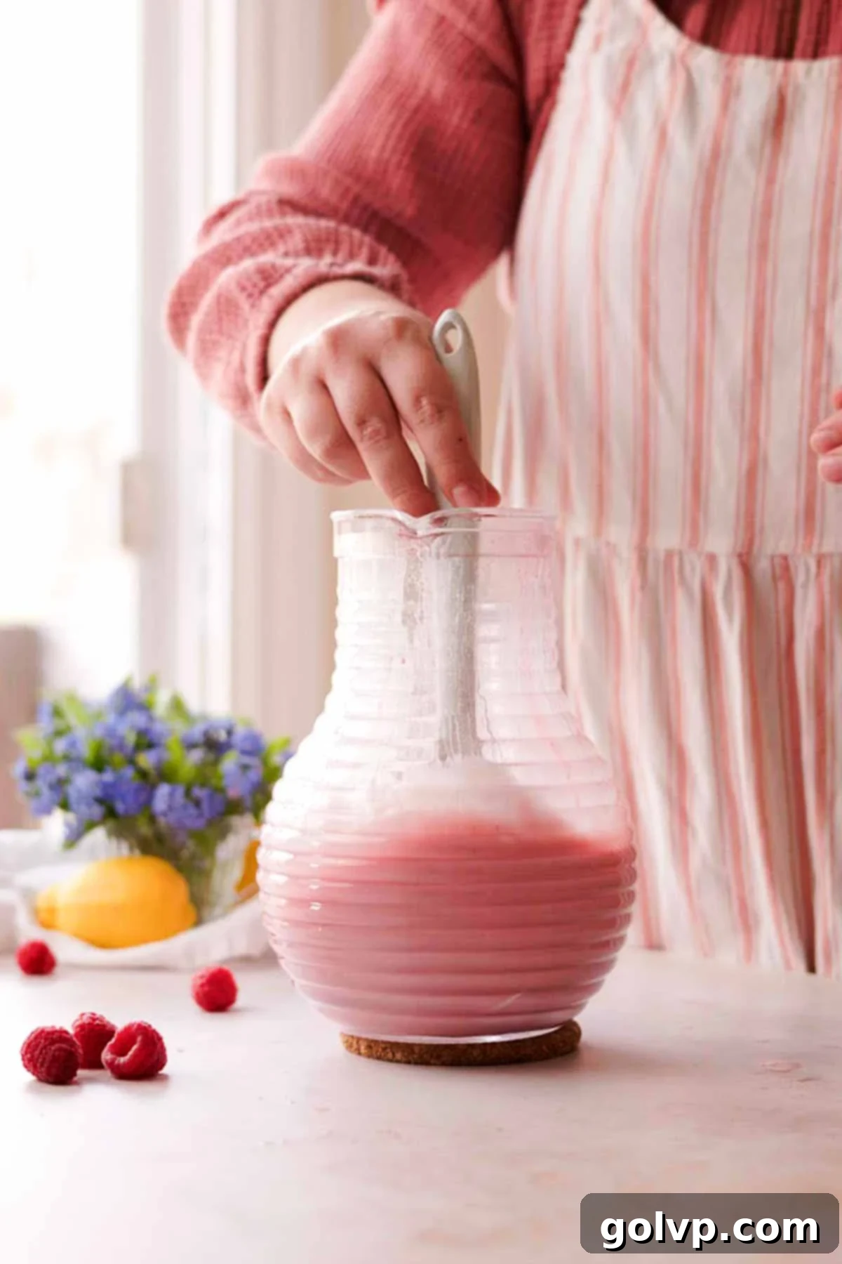 stirring raspberry posset mixture in pitcher